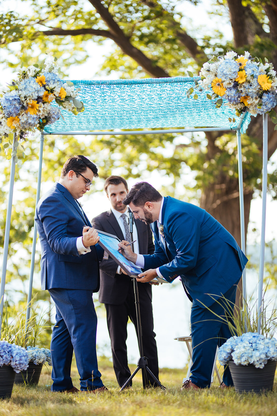 Future spouse signing large poster during wedding in Portland ME Shawnee Custalow Queer wedding photography