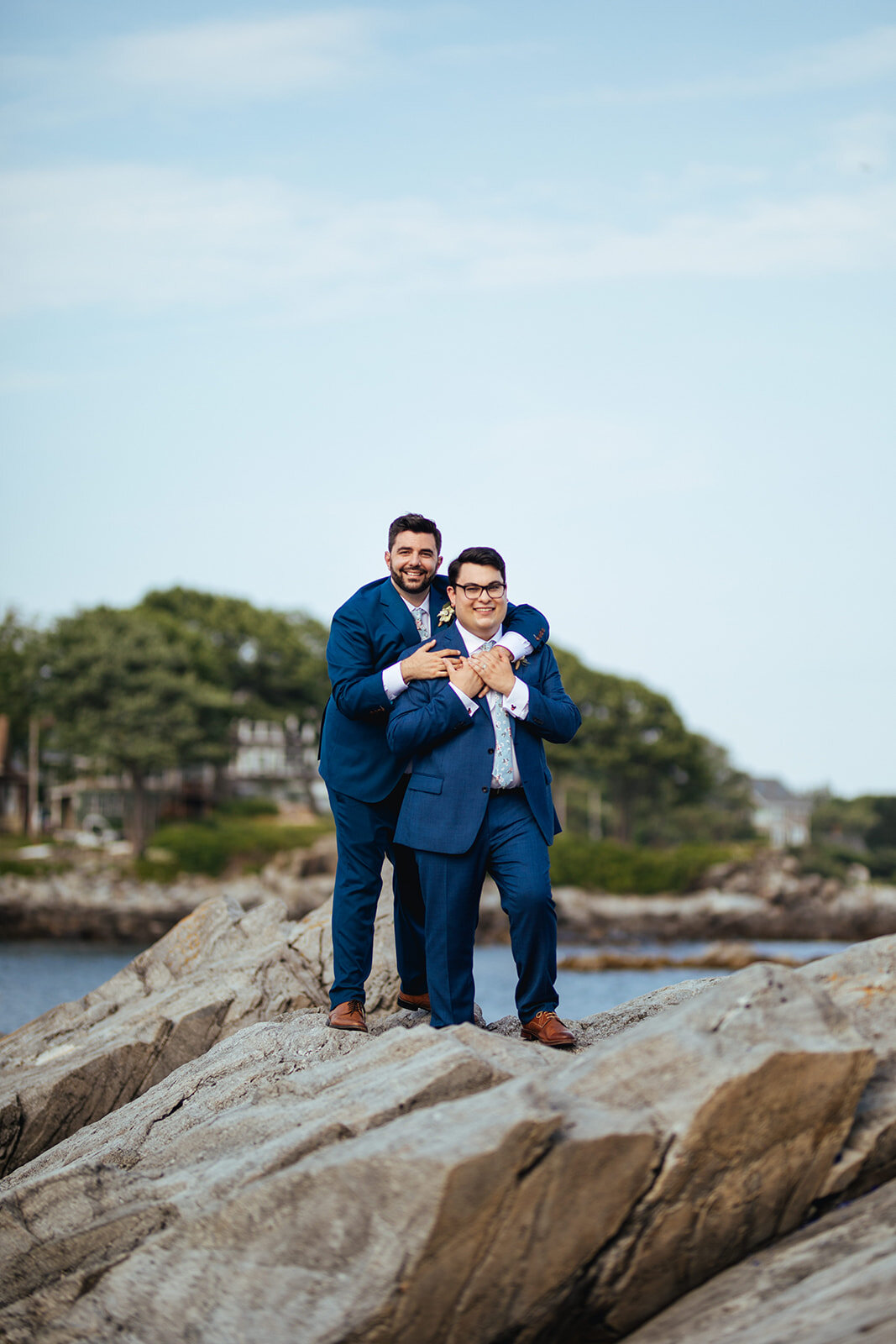 Newlyweds embracing on a rocky beach on Peaks Island Portland ME Shawnee Custalow Queer wedding photography