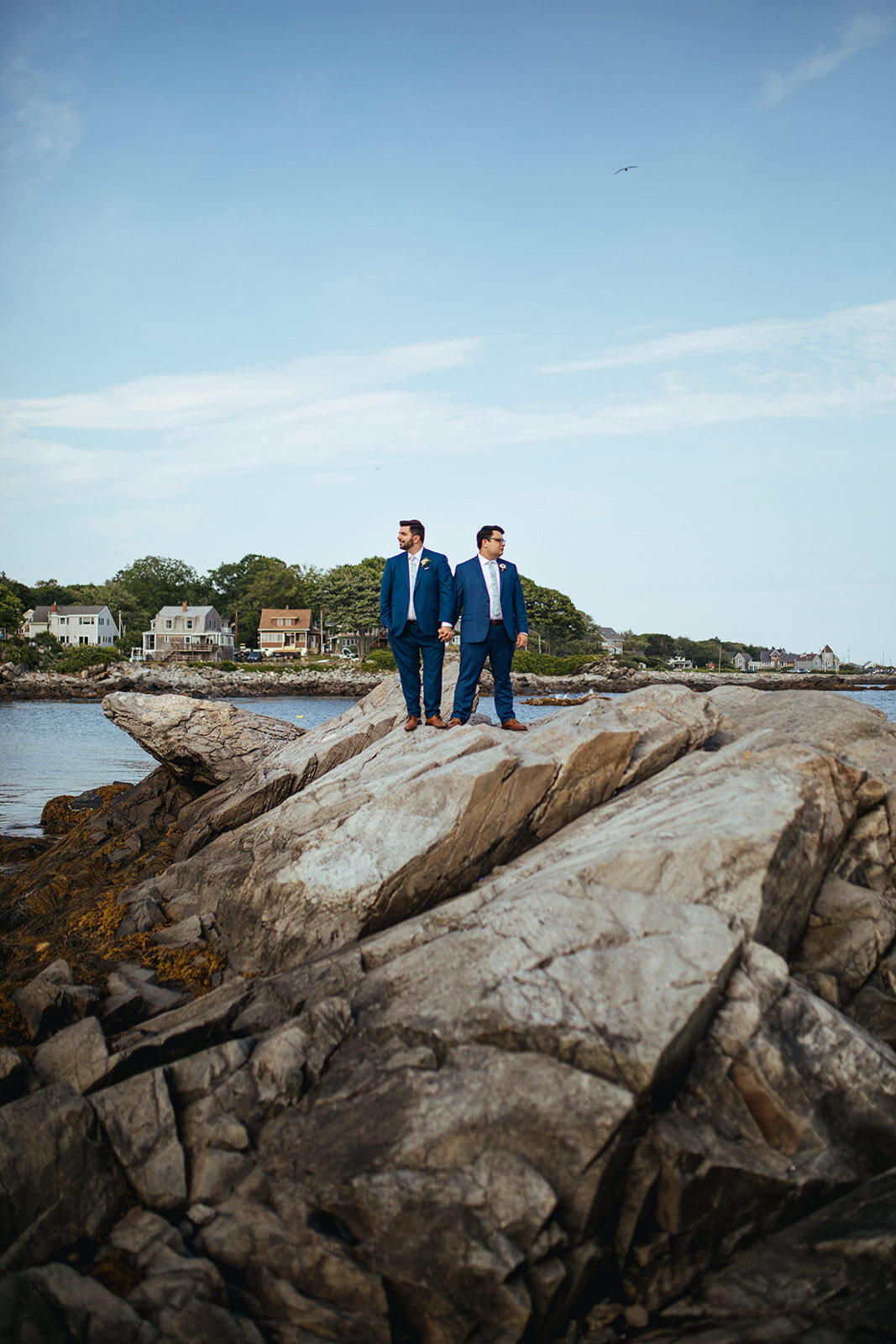 Newlyweds posing on large rock on Peaks Island Portland ME Shawnee Custalow Queer wedding photography