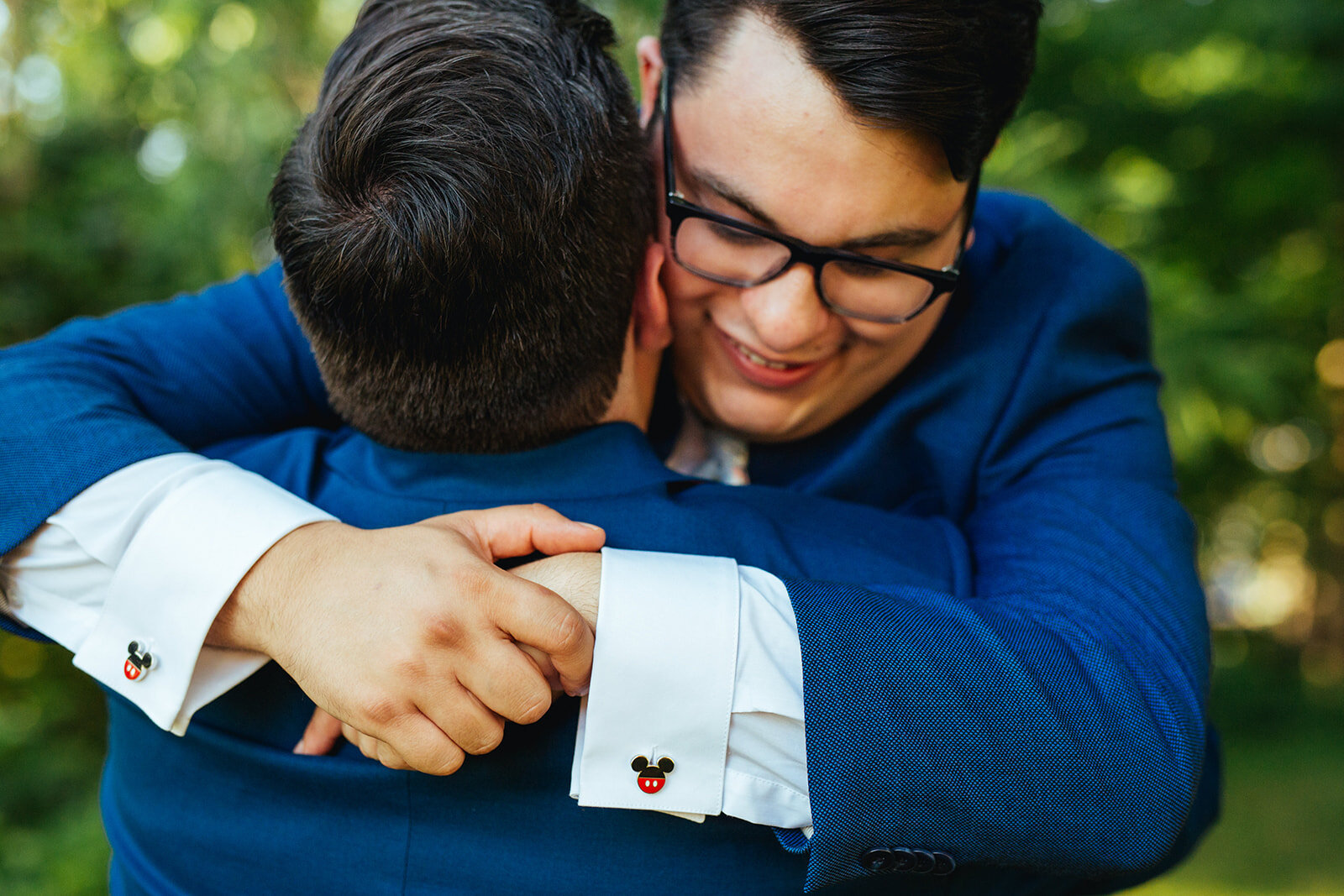 Queer newlywed grooms hugging with mickey mouse cufflinks on peaks island Portland ME Shawnee Custalow photography