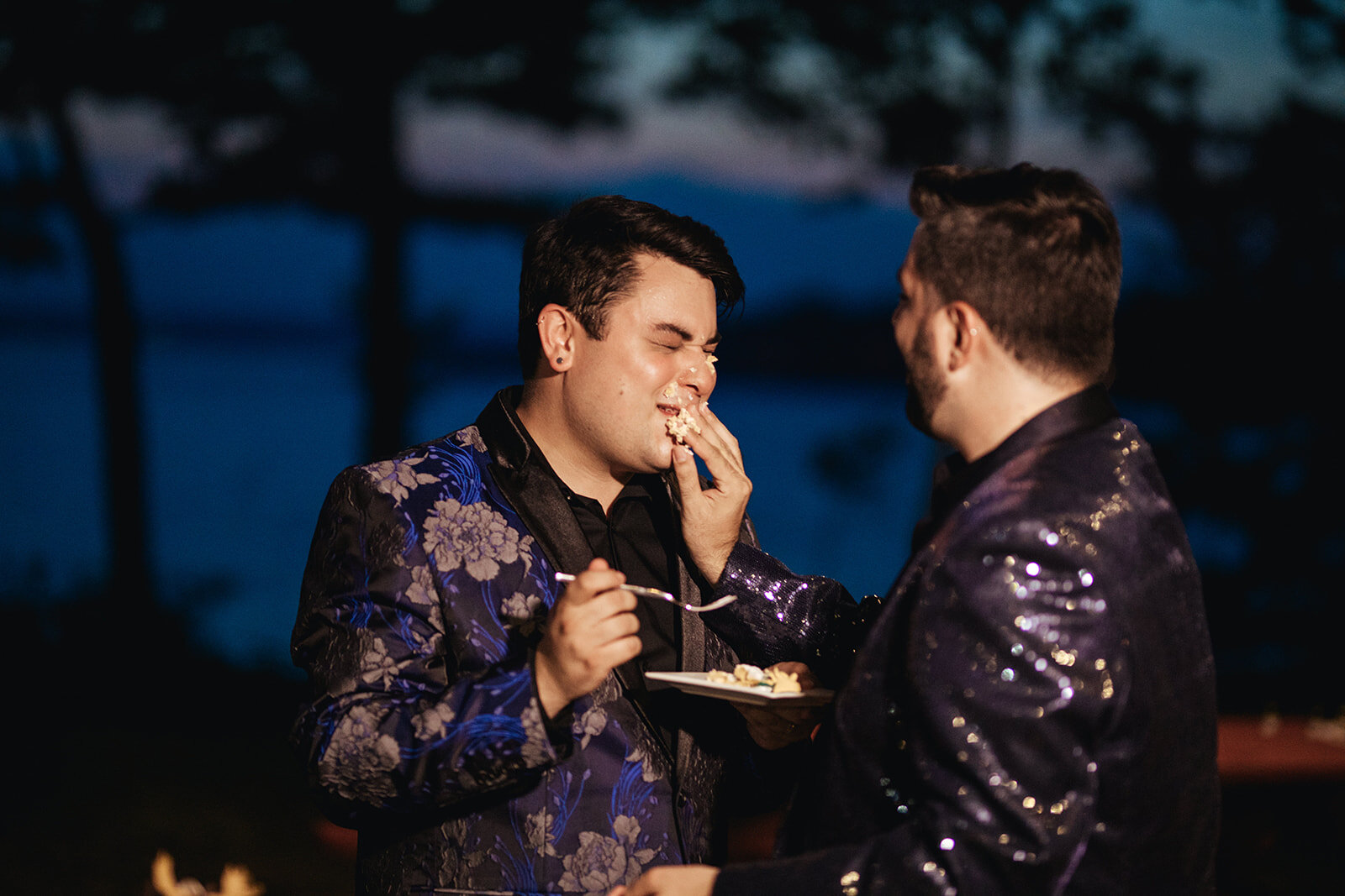 Newlywed grooms feeding each other cake in Portland ME Shawnee Custalow Queer wedding photography