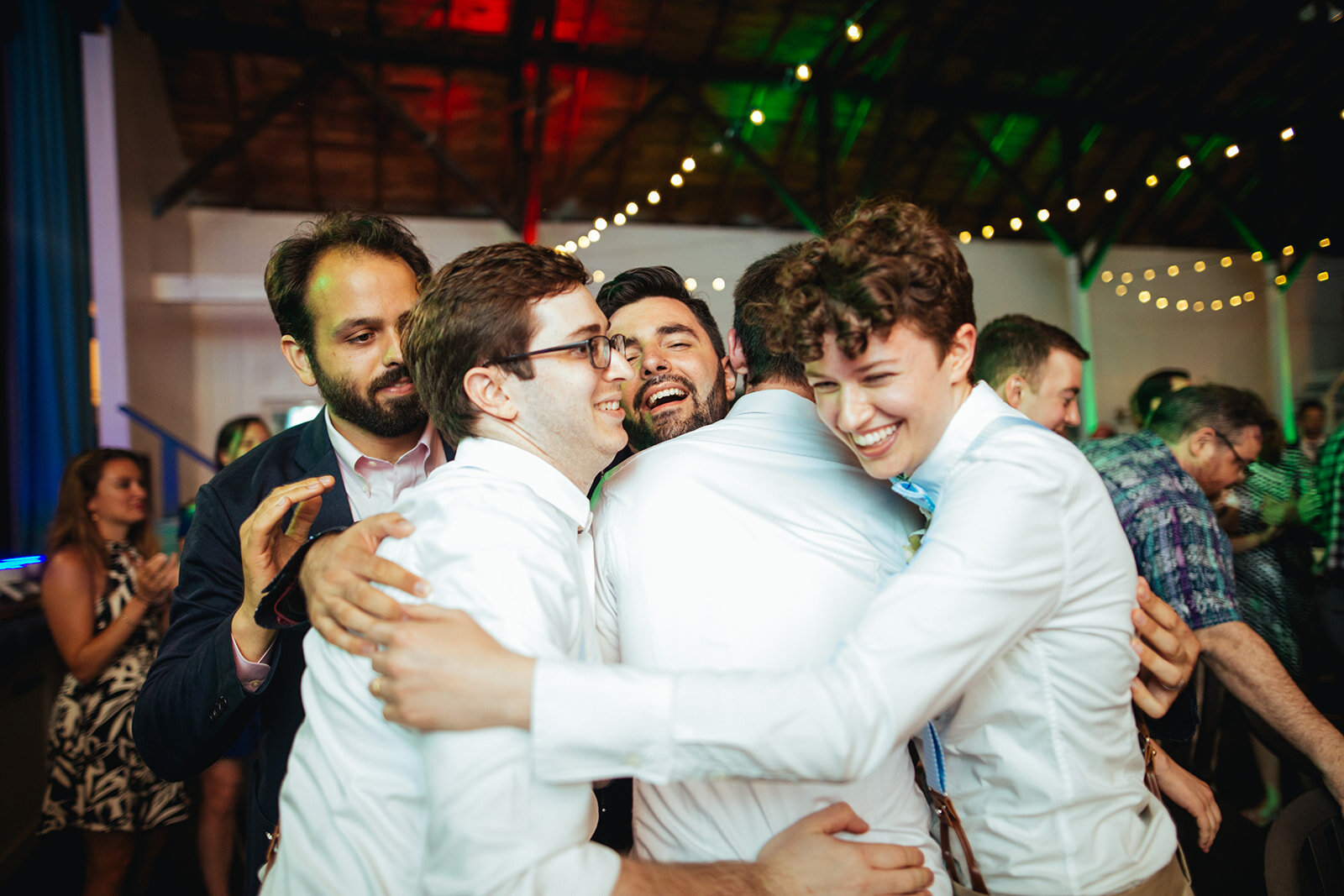 Newlywed at the center of a group hug in Portland ME Shawnee Custalow Queer wedding photography