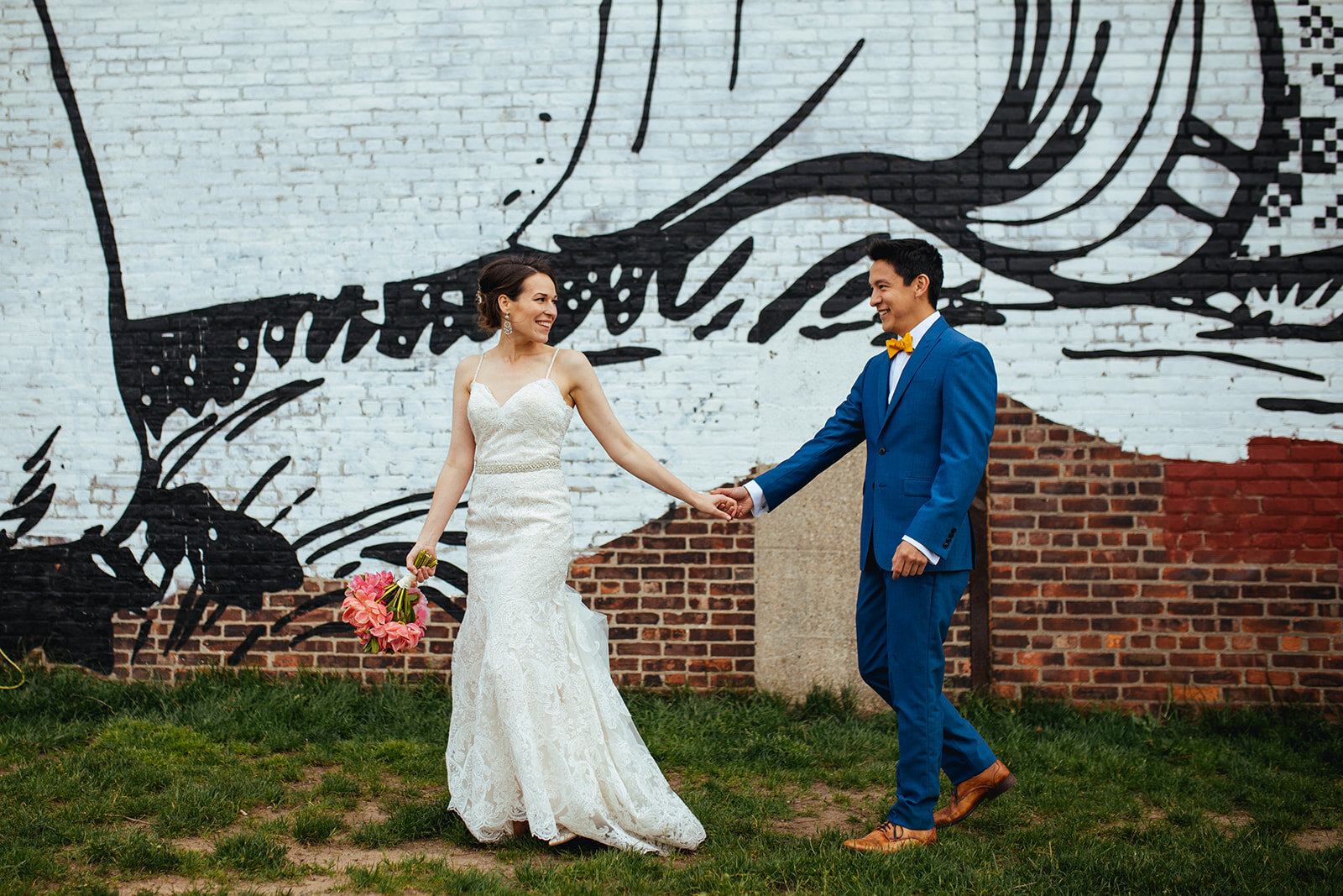Future spouses holding hands by a mural in Brooklyn NY Shawnee Custalow wedding photography