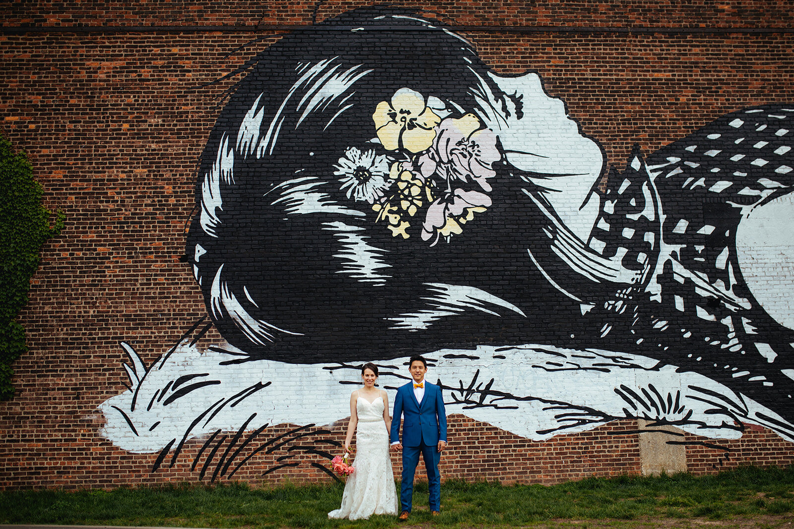 Future spouses holding hands by a mural in Brooklyn NY Shawnee Custalow wedding photography