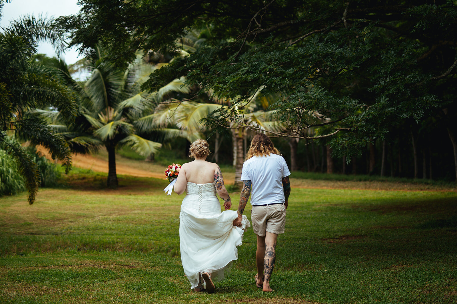 Newlyweds walking through a field in Kauai Hawaii Shawnee Custalow wedding photography