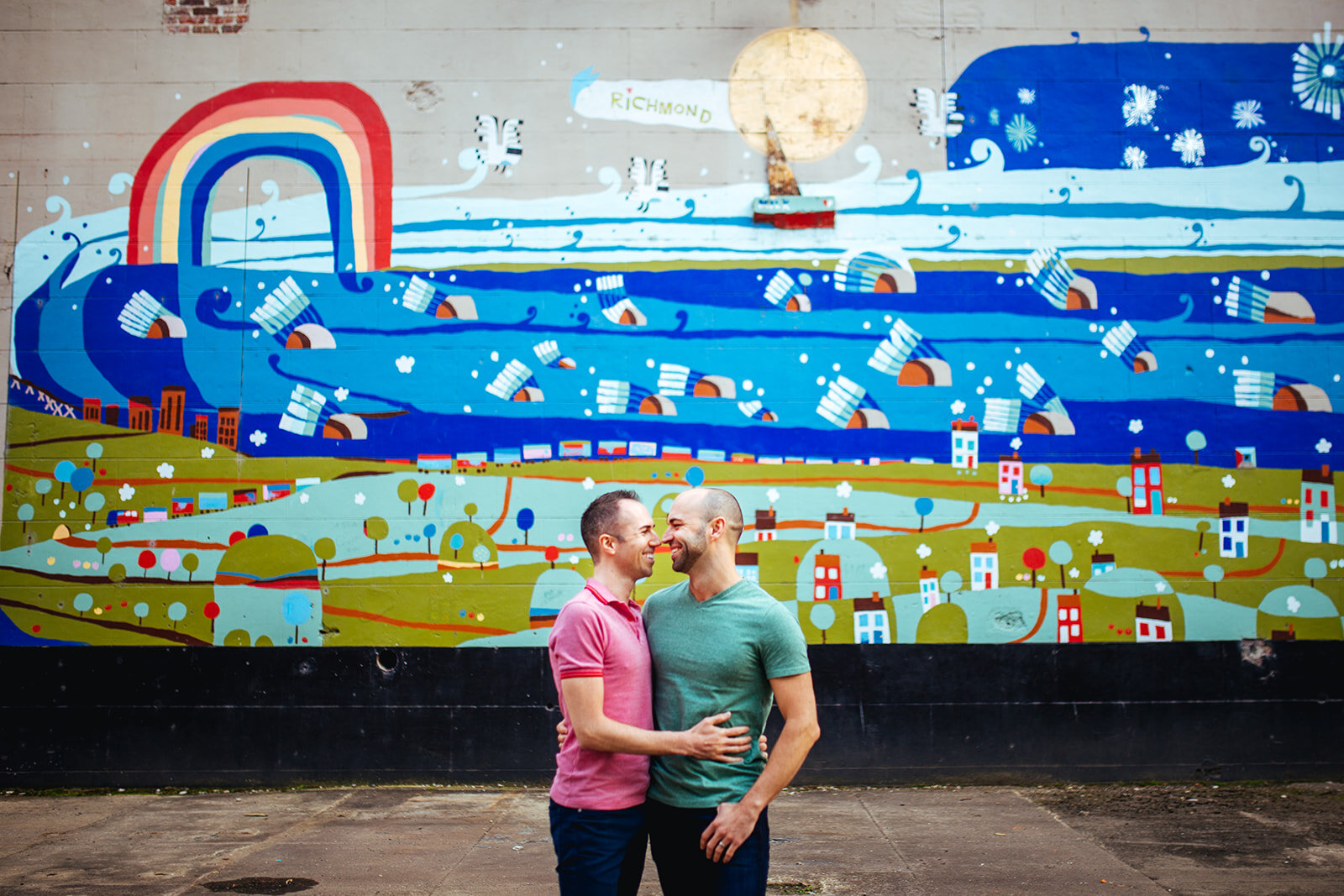 Queer Couple embracing under a colorful mural in Richmond VA Shawnee Custalow photography