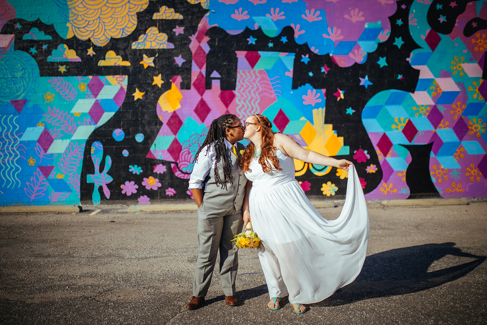 LGBTQ spouses kissing by mural in Norfolk VA Shawnee Custalow queer wedding photography