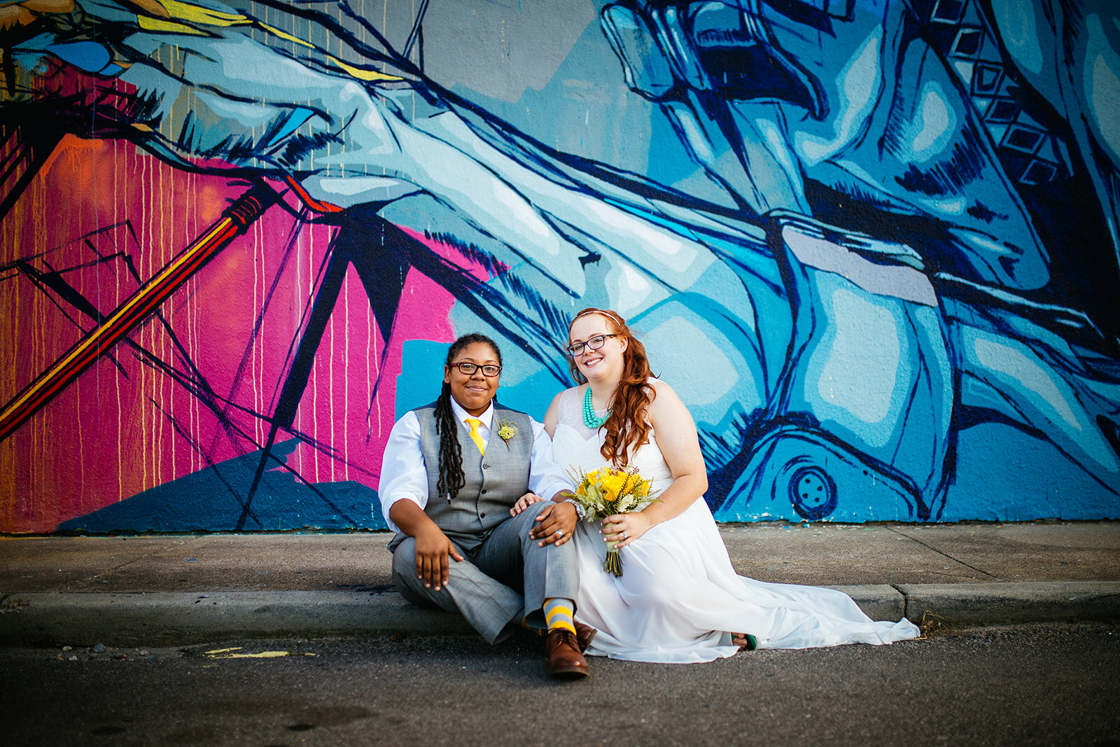 LGBTQ Newlyweds sitting under a mural in Norfolk VA Shawnee Custalow photography