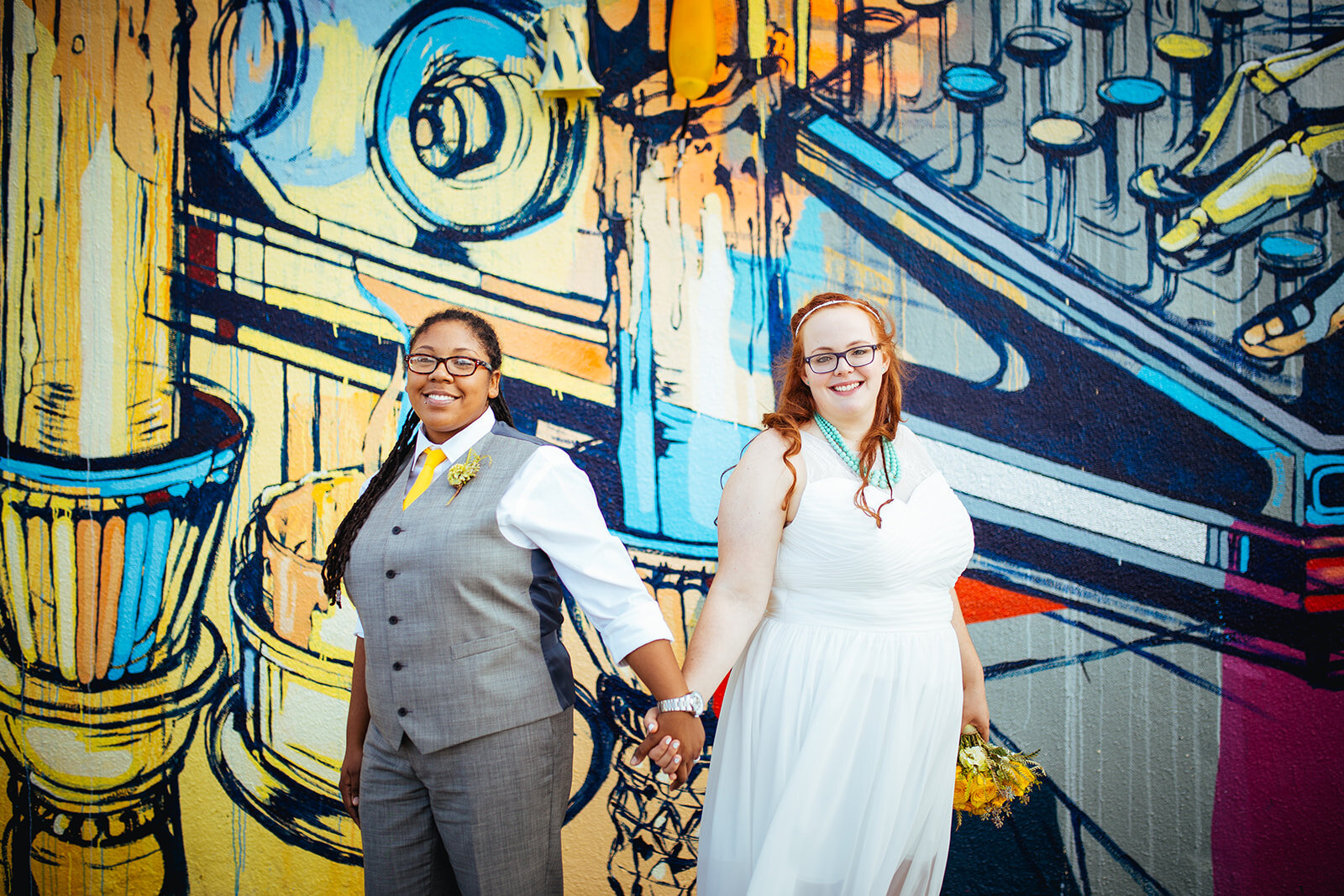 Newlyweds holding hands by a mural in Norfolk VA Shawnee Custalow photographer