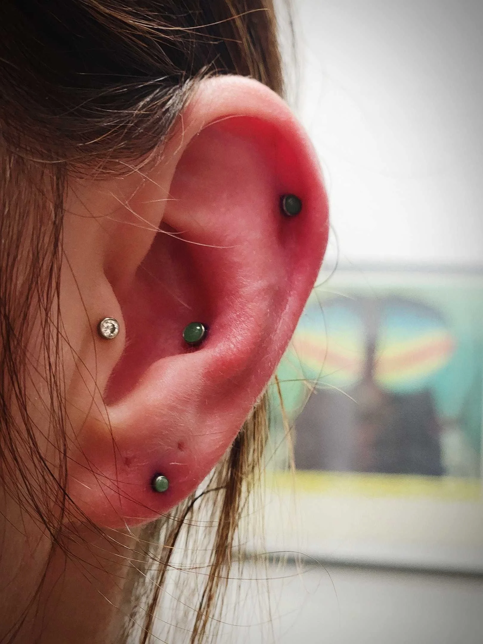 Close-up of a human ear with multiple piercings featuring various stud earrings.