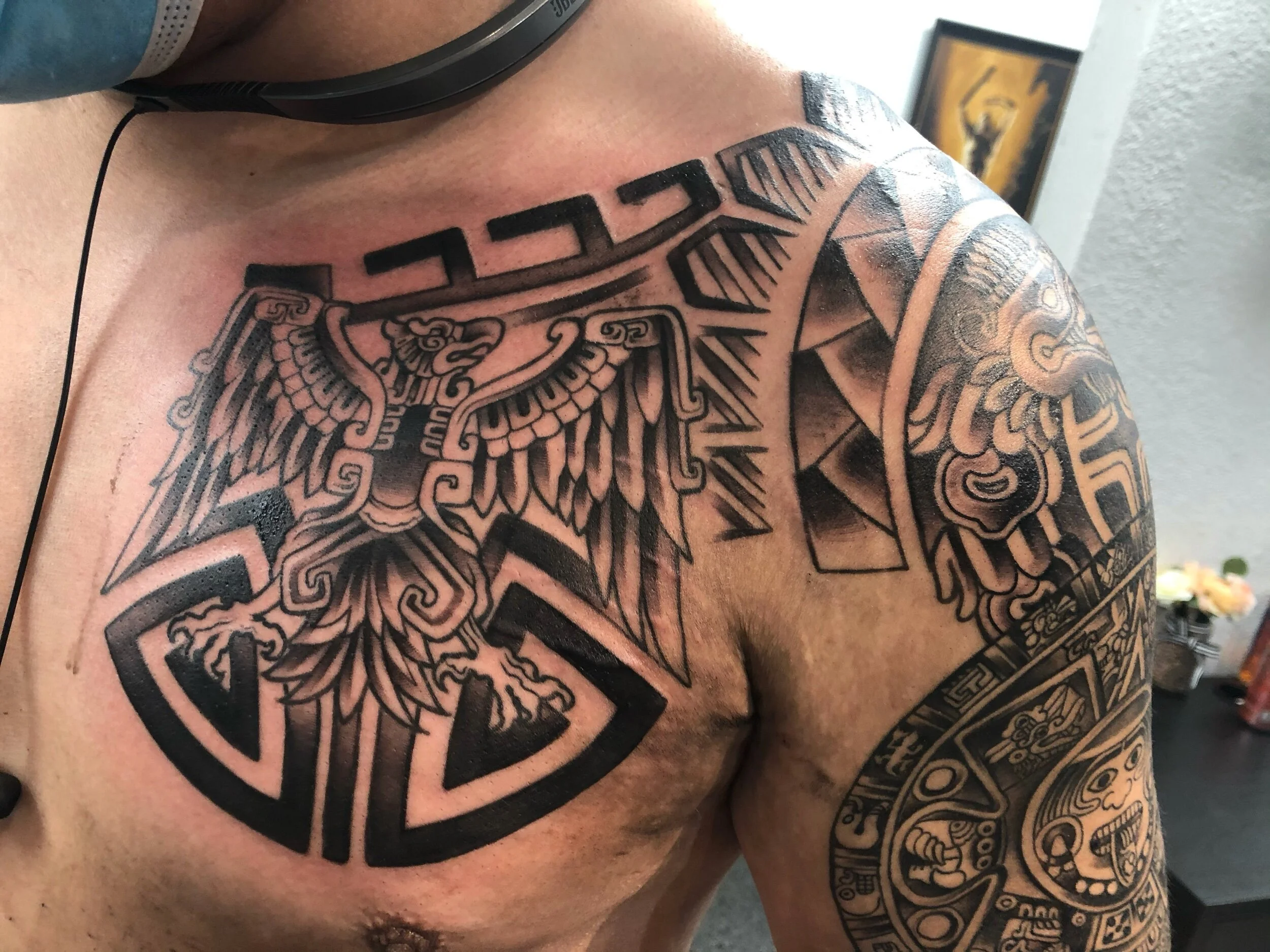 Aztec-inspired tattoo design on chest and shoulder