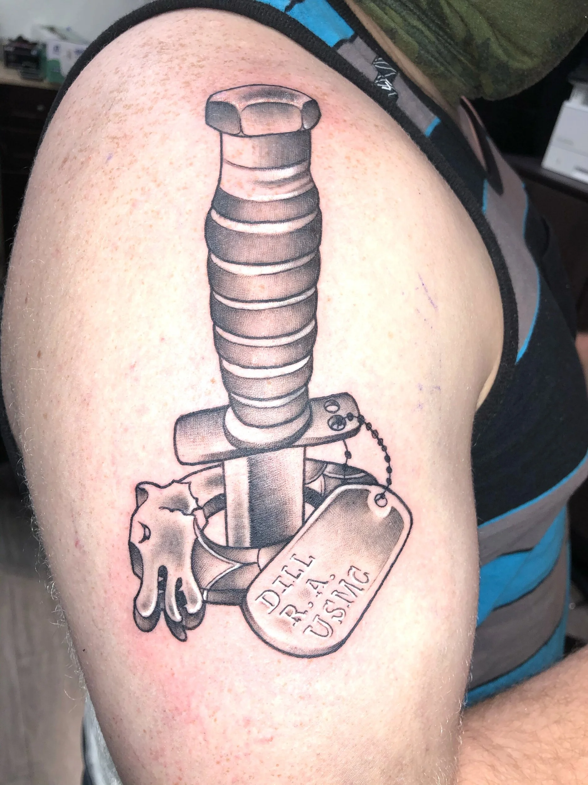 Tattoo of a Ka-Bar knife with dog tags and glove on arm.