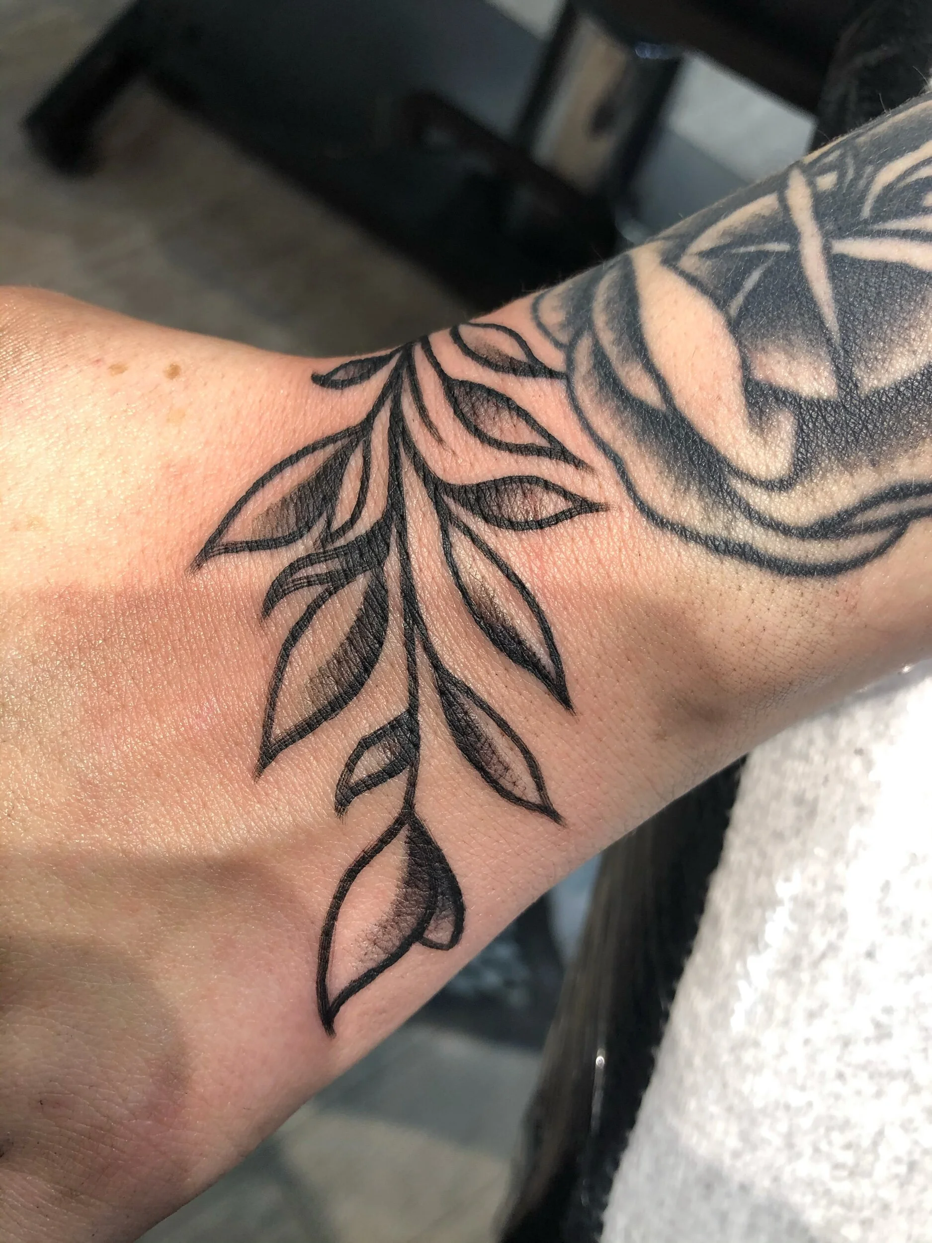 Wrist tattoo featuring floral design with leaves and petals.
