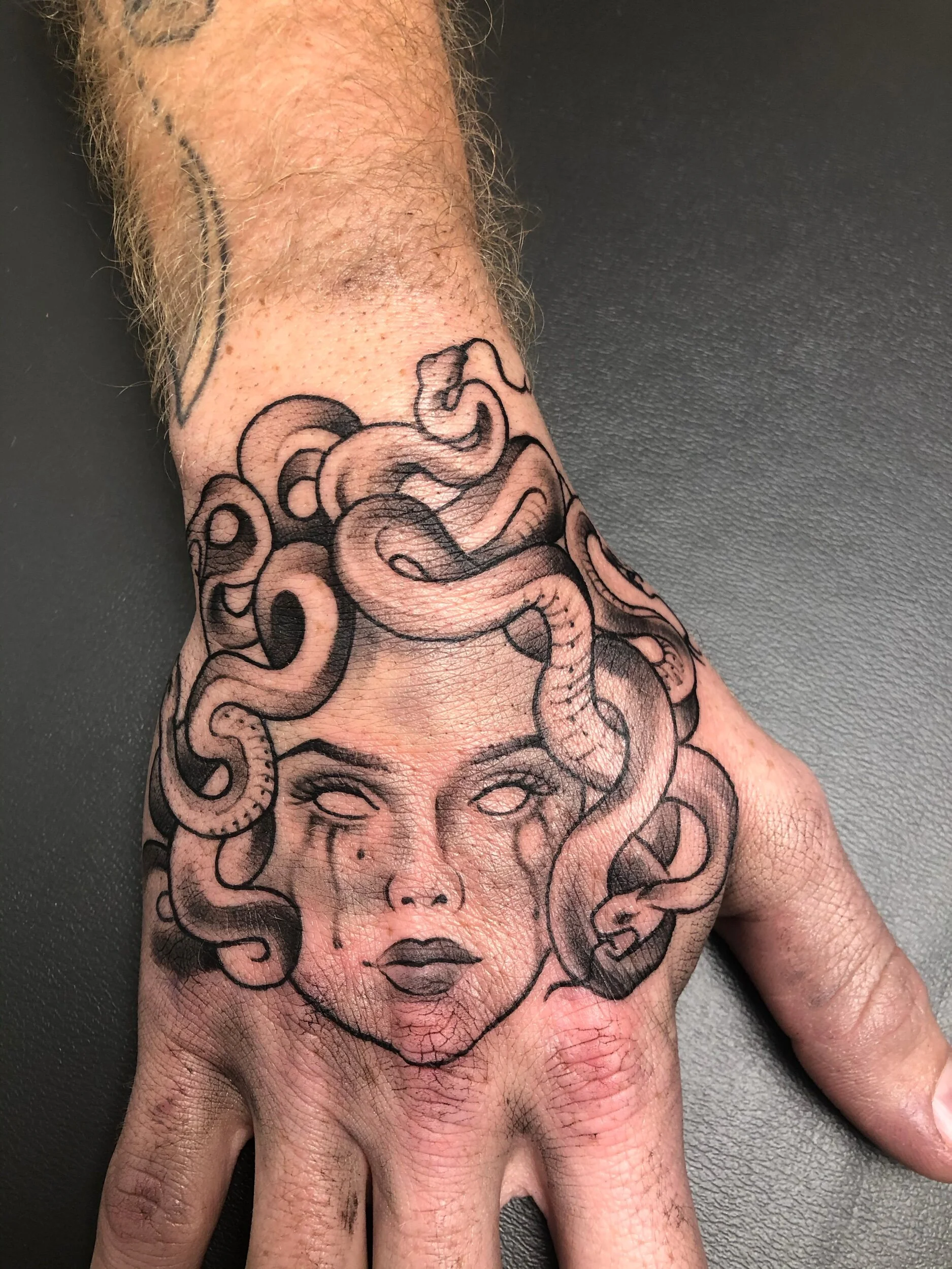 Tattoo of Medusa with snakes for hair on a person's hand
