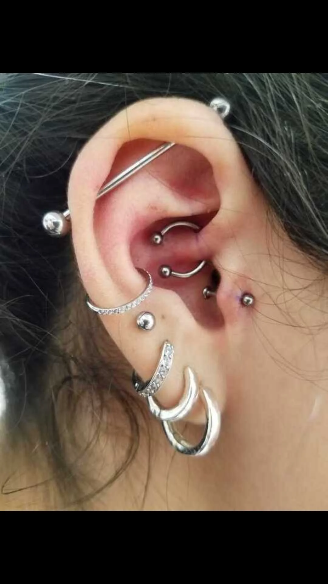 Close-up of an ear with multiple piercings and jewelry.