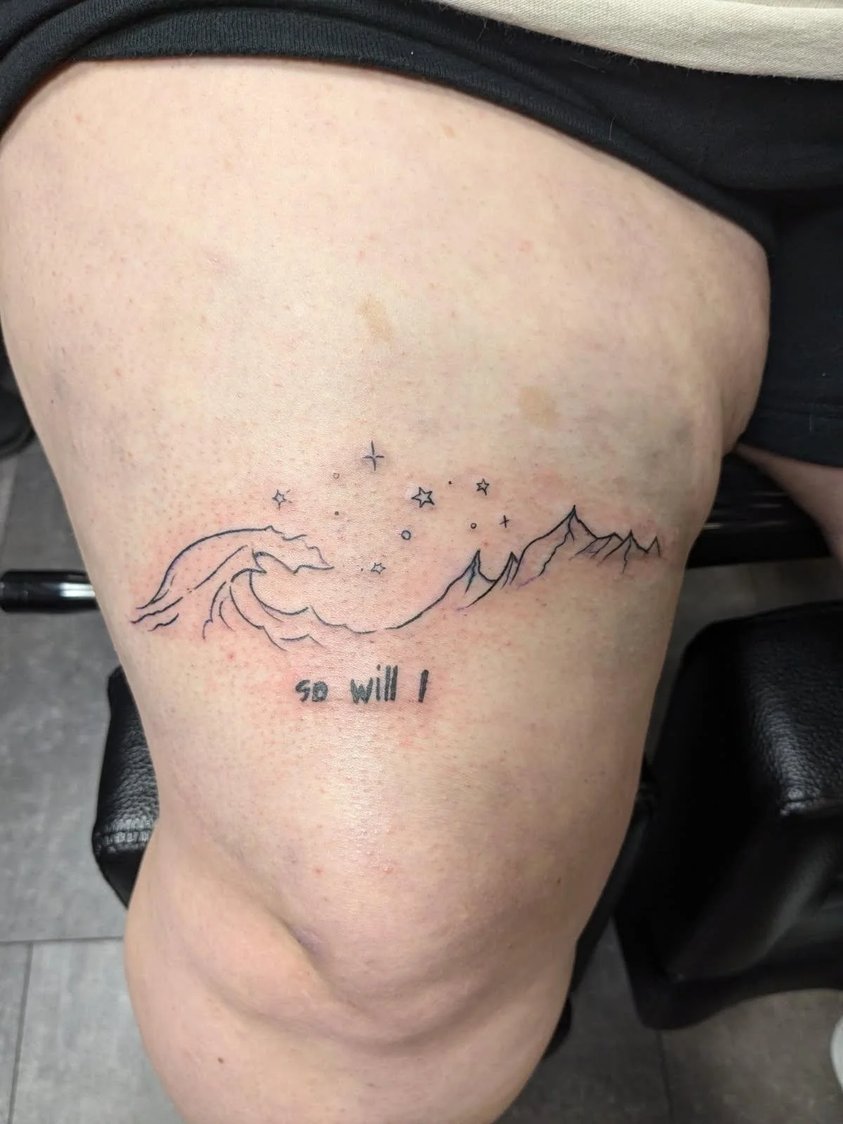 Tattoo of mountains, stars, and the moon with the phrase 'so will I' on a person's upper thigh.