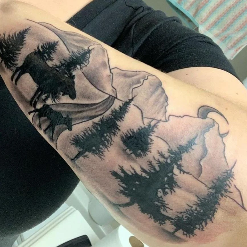 Tattoo of a moose and trees on an arm