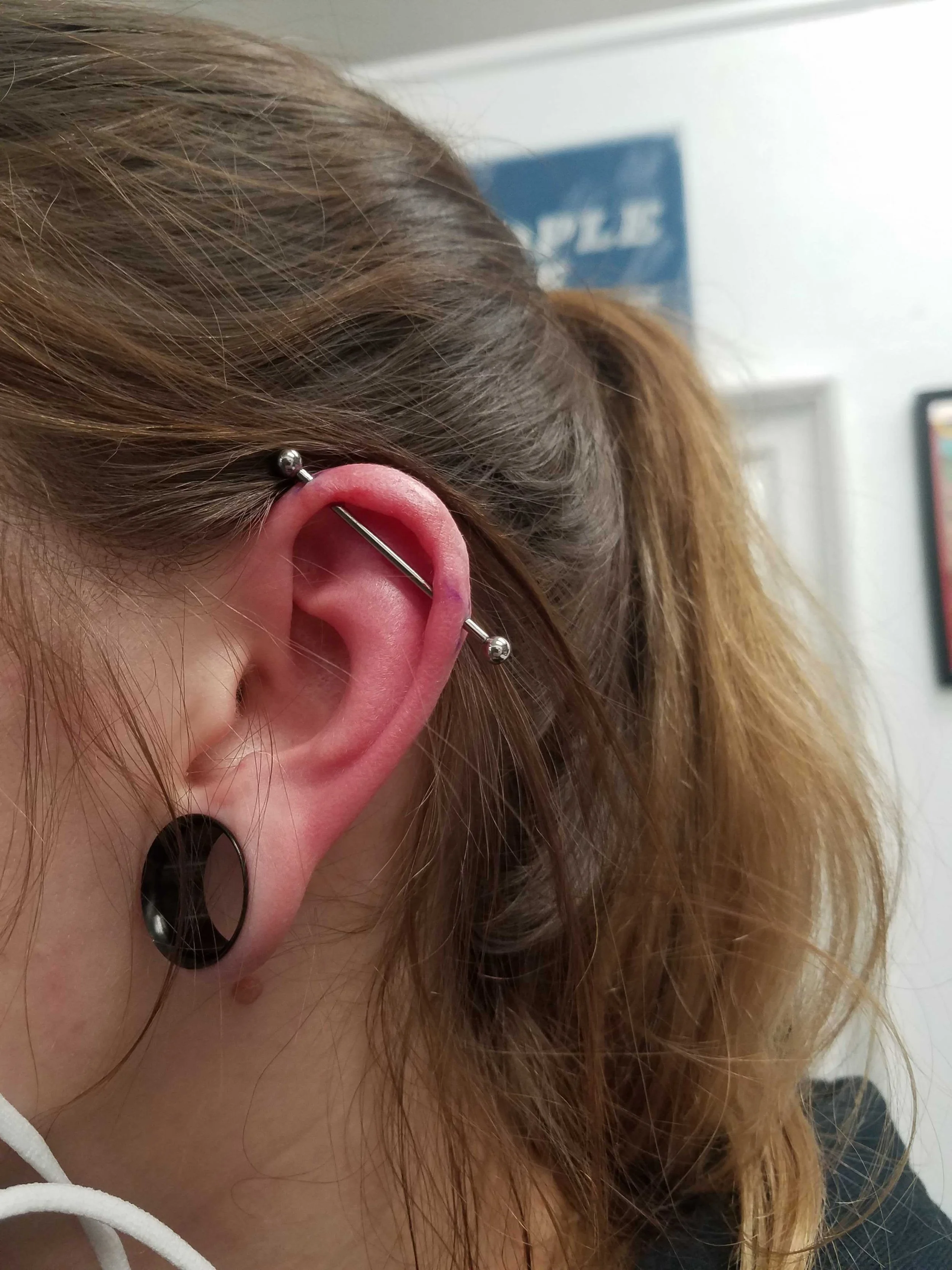 Close-up of an ear with industrial and stretched lobe piercings