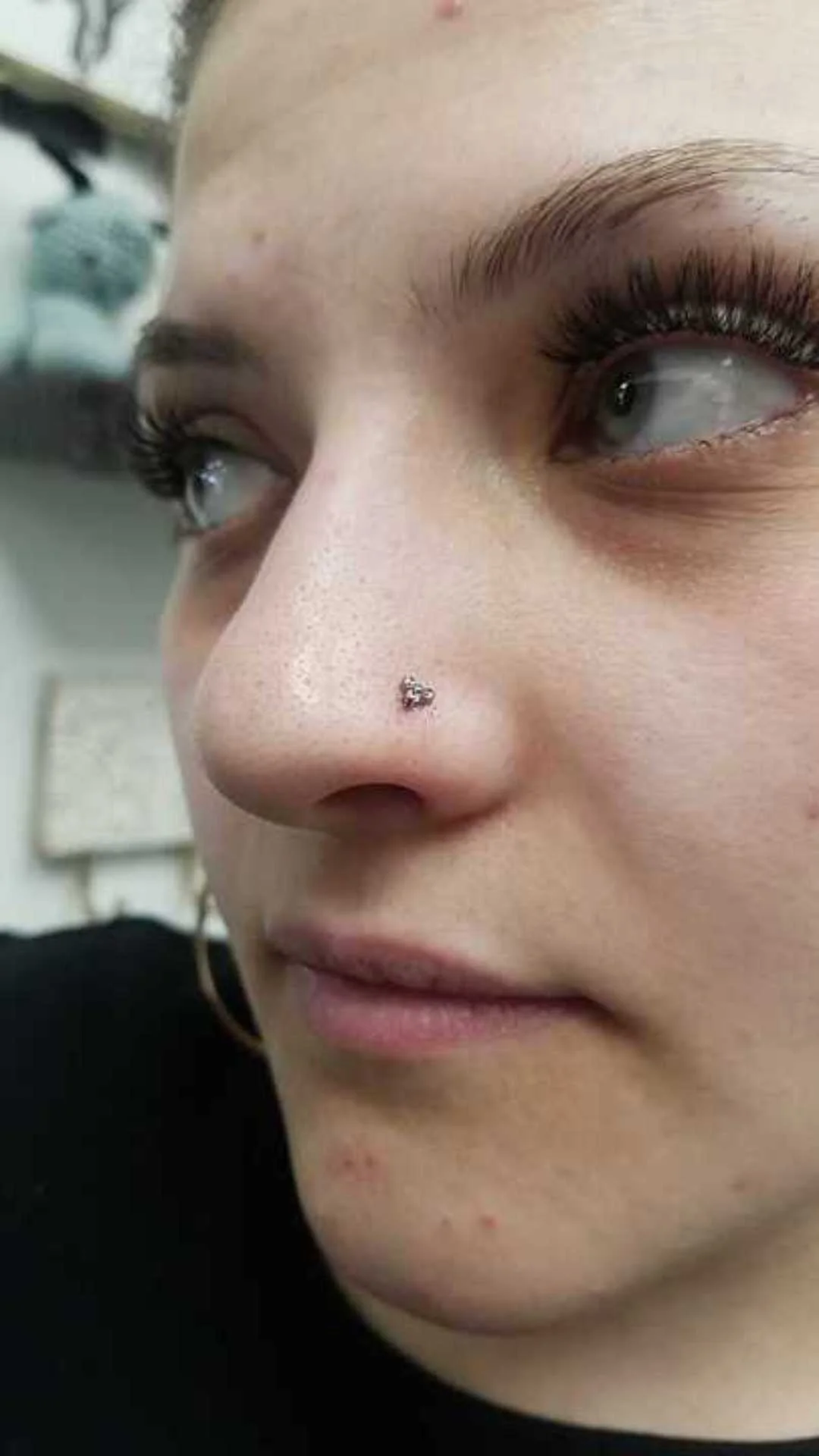 Close-up of a person with a nose piercing and thick eyelashes