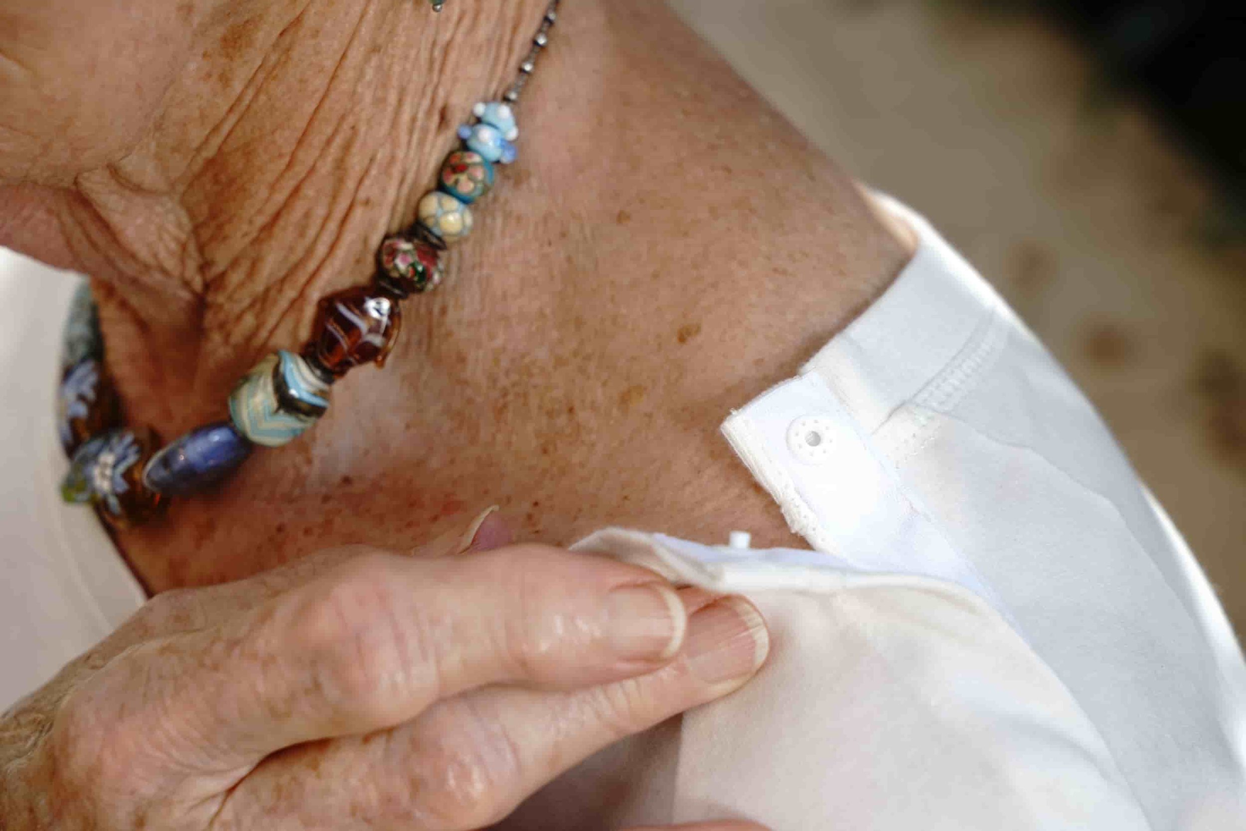 A close up of someone closing a press-stud on the shoulder of a top.
