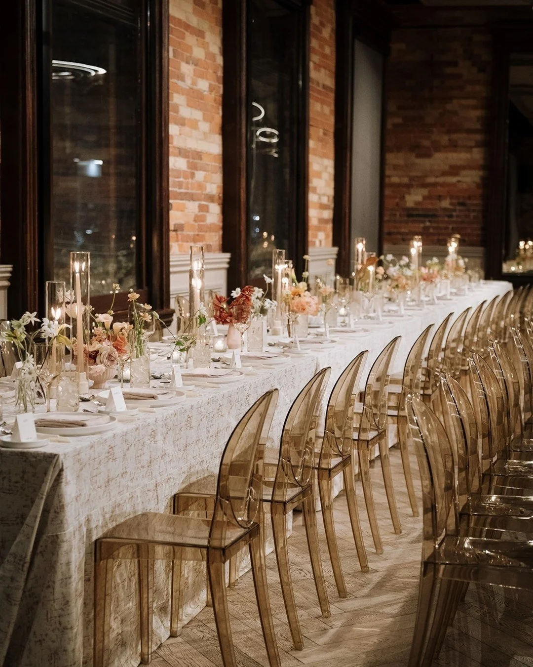This Gladstone House wedding blends warm red tones with fall-inspired elegance. Etched rose and cream velvet linens paired with gold ghost chairs create a luxurious, modern feel, while structural centerpieces prove that minimalism can still be impact