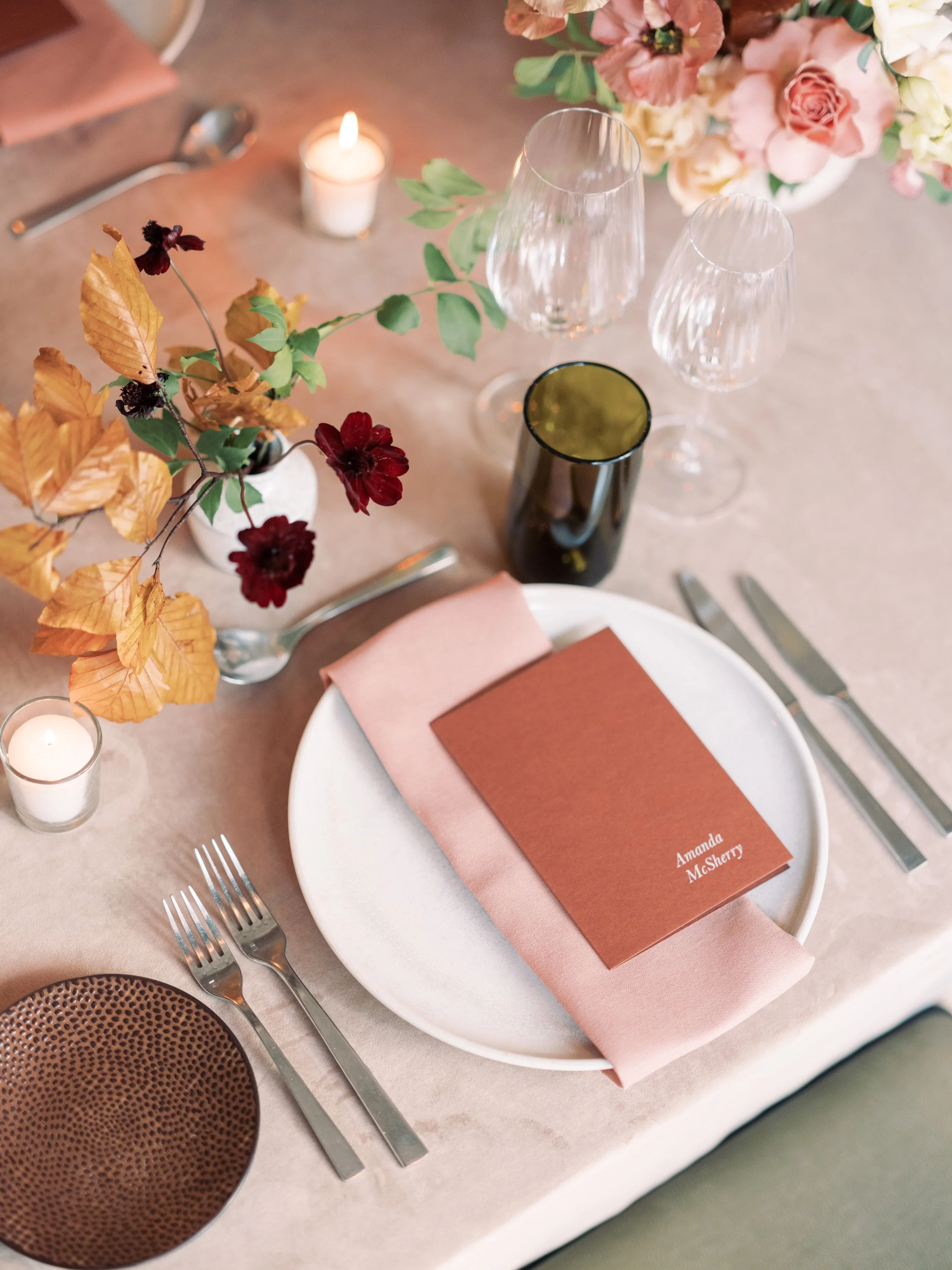 A place setting in terracotta colours with fall inspired flowers.