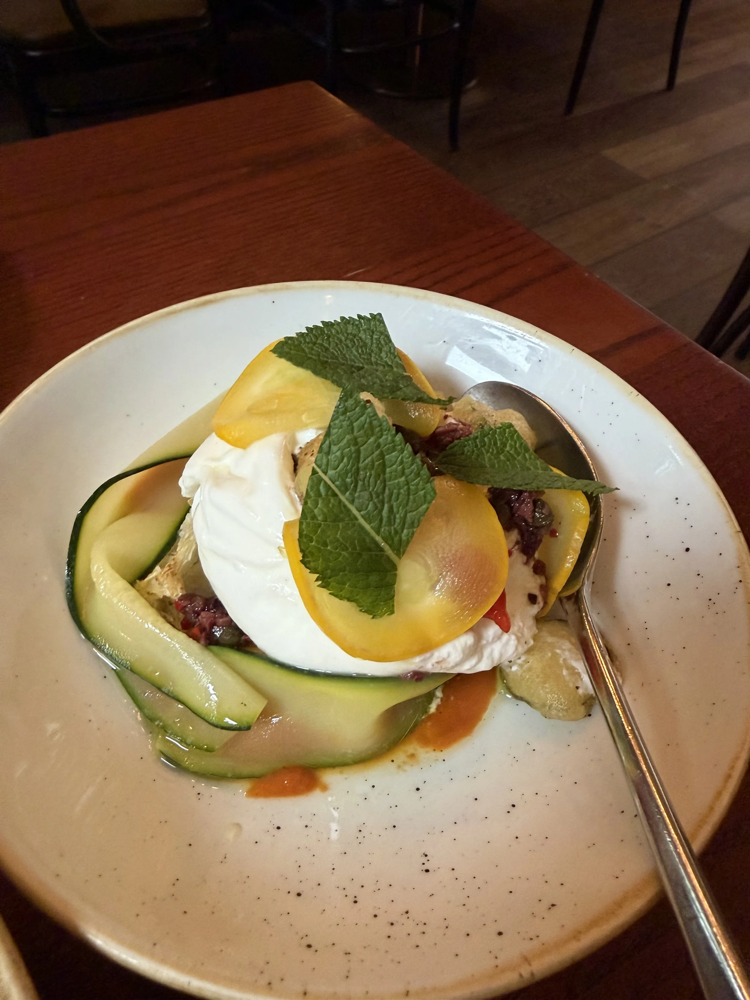 Burrata, Red Pepper Purée, Black Olive Salsa, Courgettes & Focaccia on a serving plate