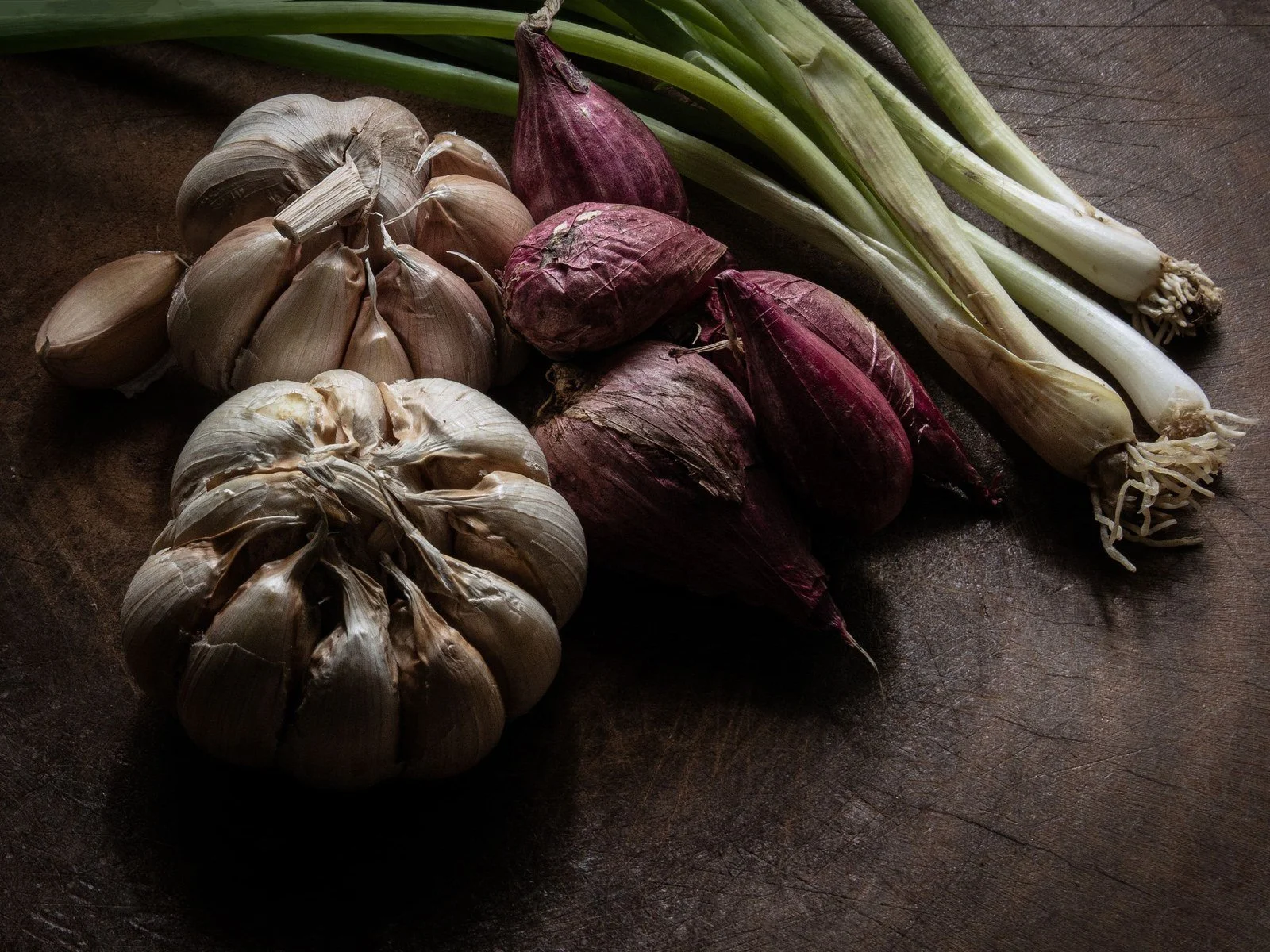 Fresh garlic and onions on dark wood