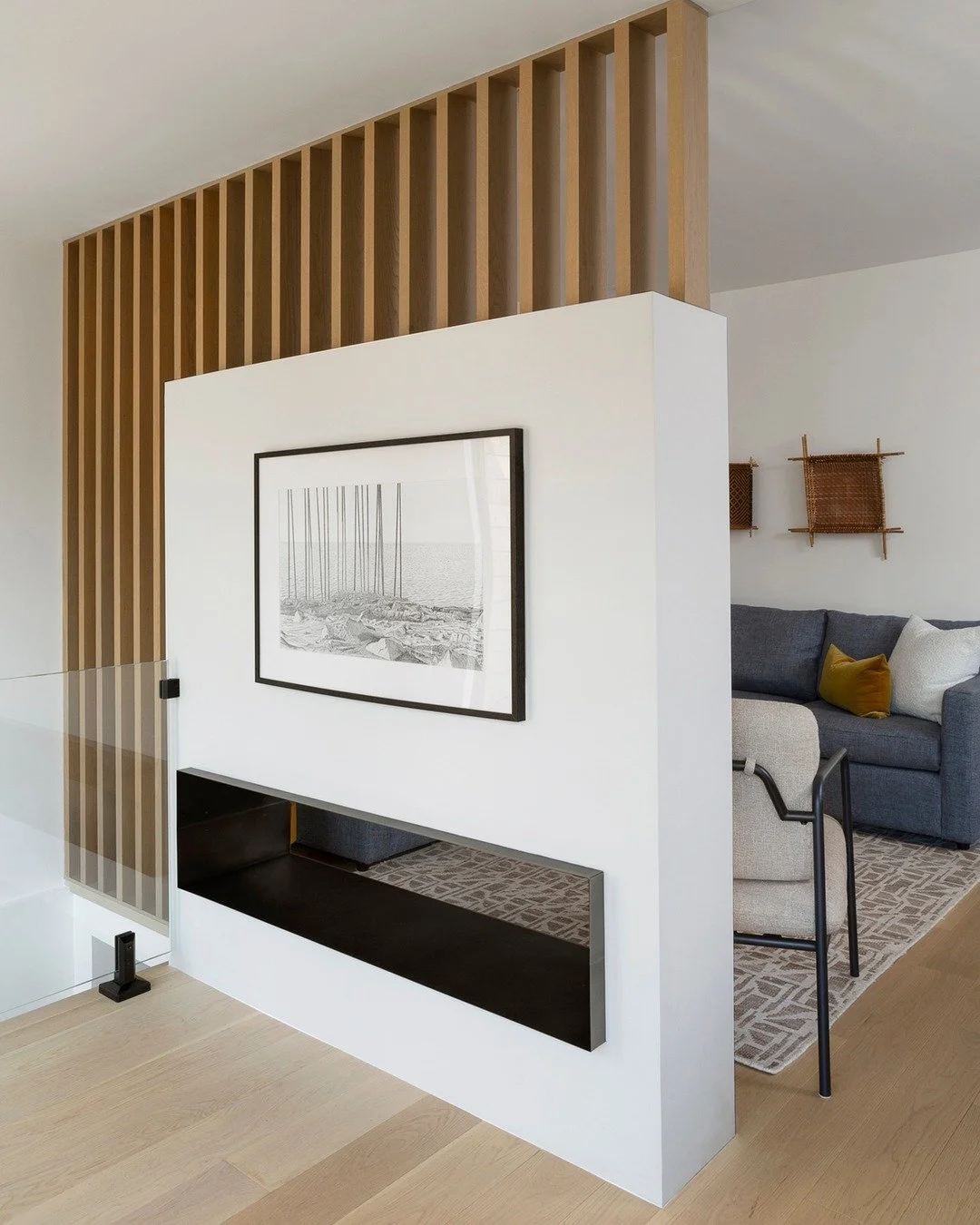This partition wall at Gloucester is one of those design choices that changed everything.

We needed to separate spaces, but a solid wall would have felt heavy. Instead, we created something layered: art on one side, the TV on the other, and slatted 