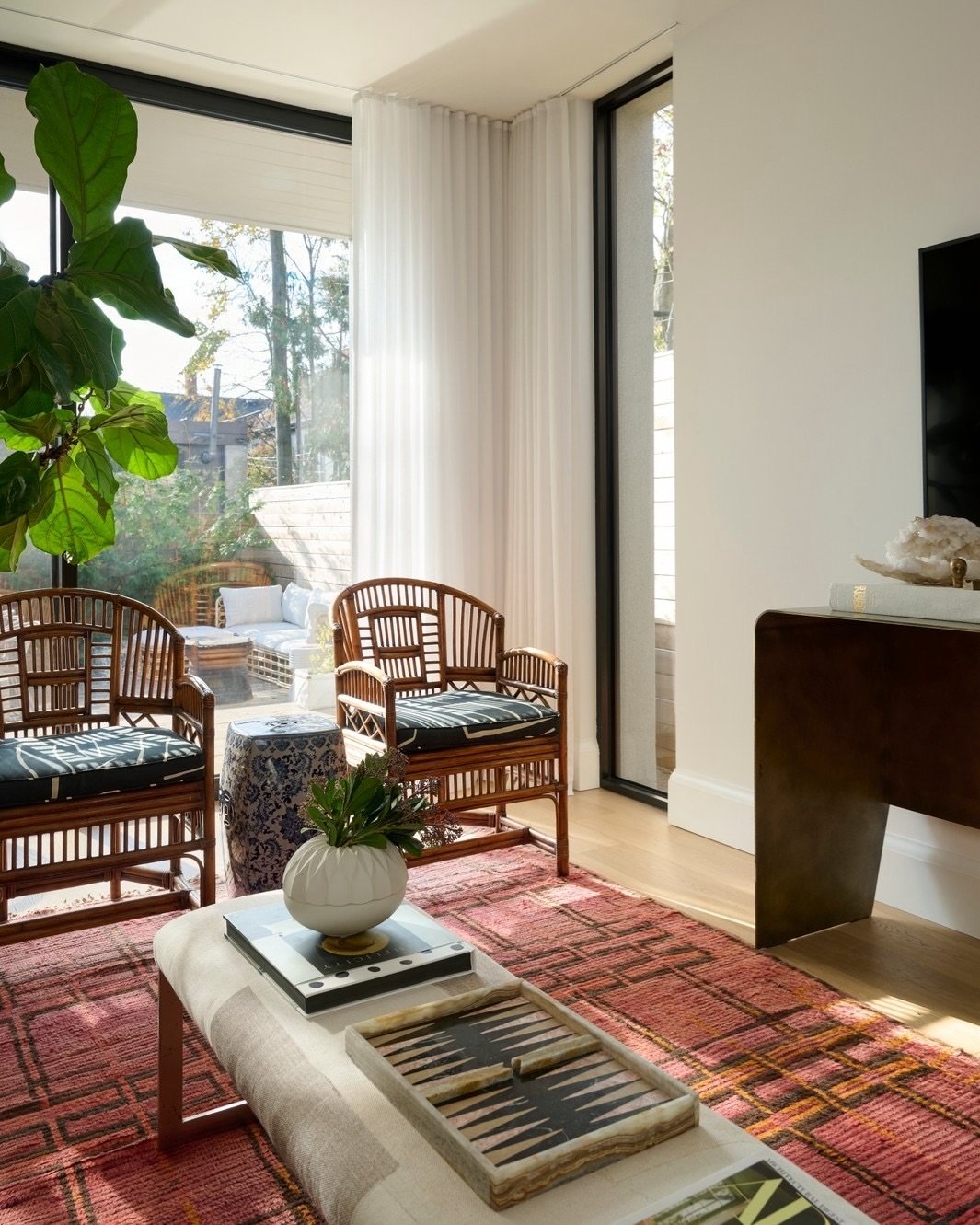 This space is a great example of mixing eras and silhouettes in interior design. The carved side table and sculptural brass lamp play beautifully against the streamlined sofa, while the patterned armchair adds just enough contrast without overwhelmin