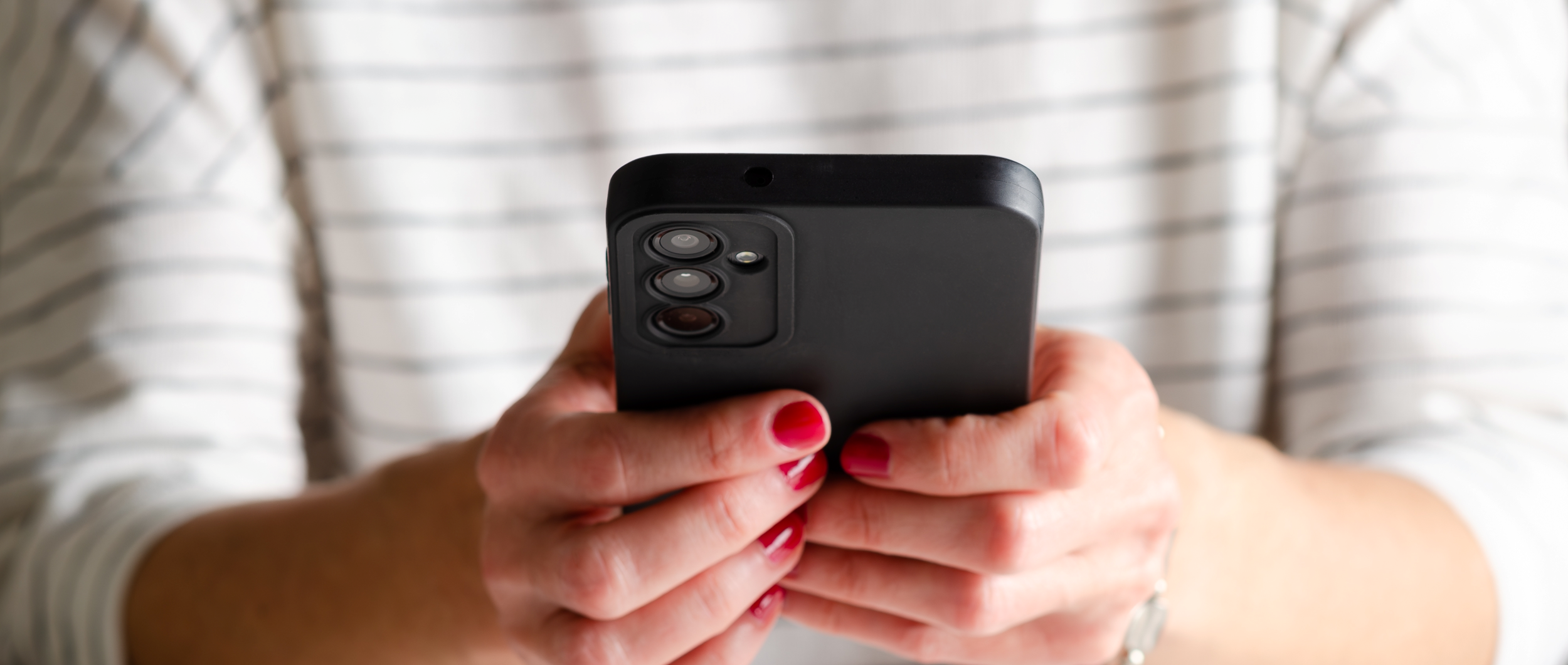 Hands of a woman holding a cell phone 2500x1651.png