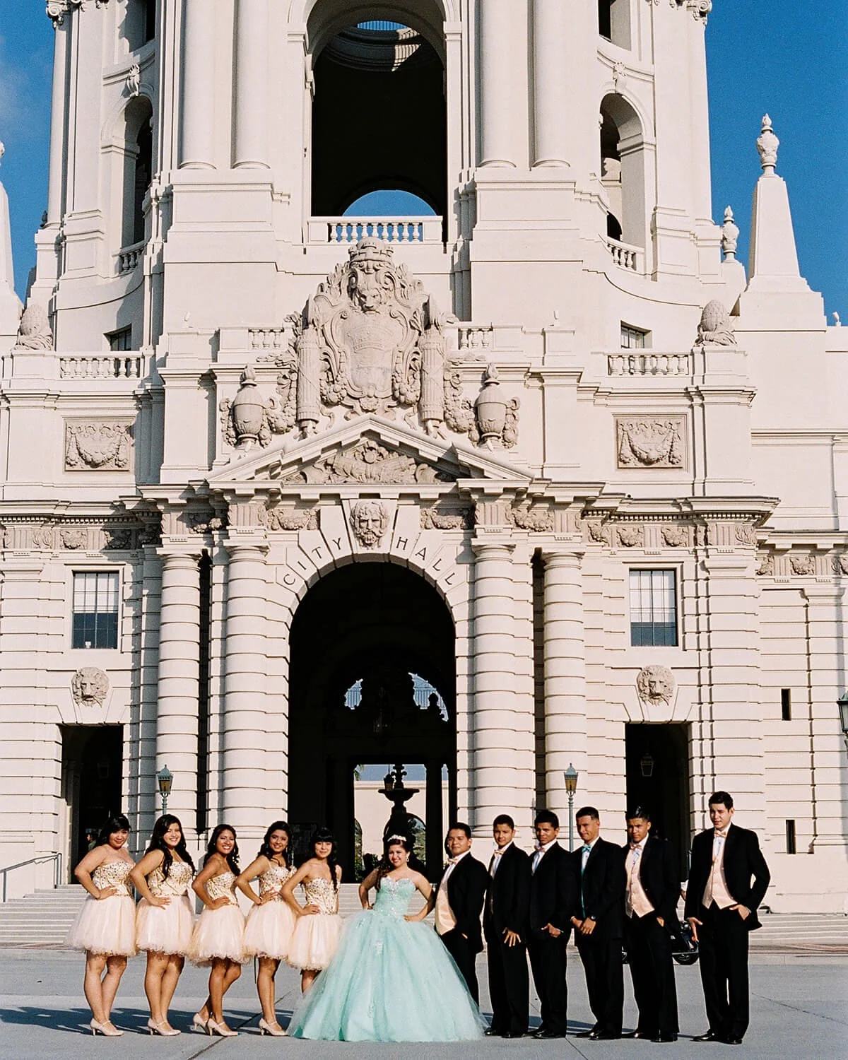 A Quinceañera Court posing in front of the historic Pasadena City Hall building with grand architectural details.
