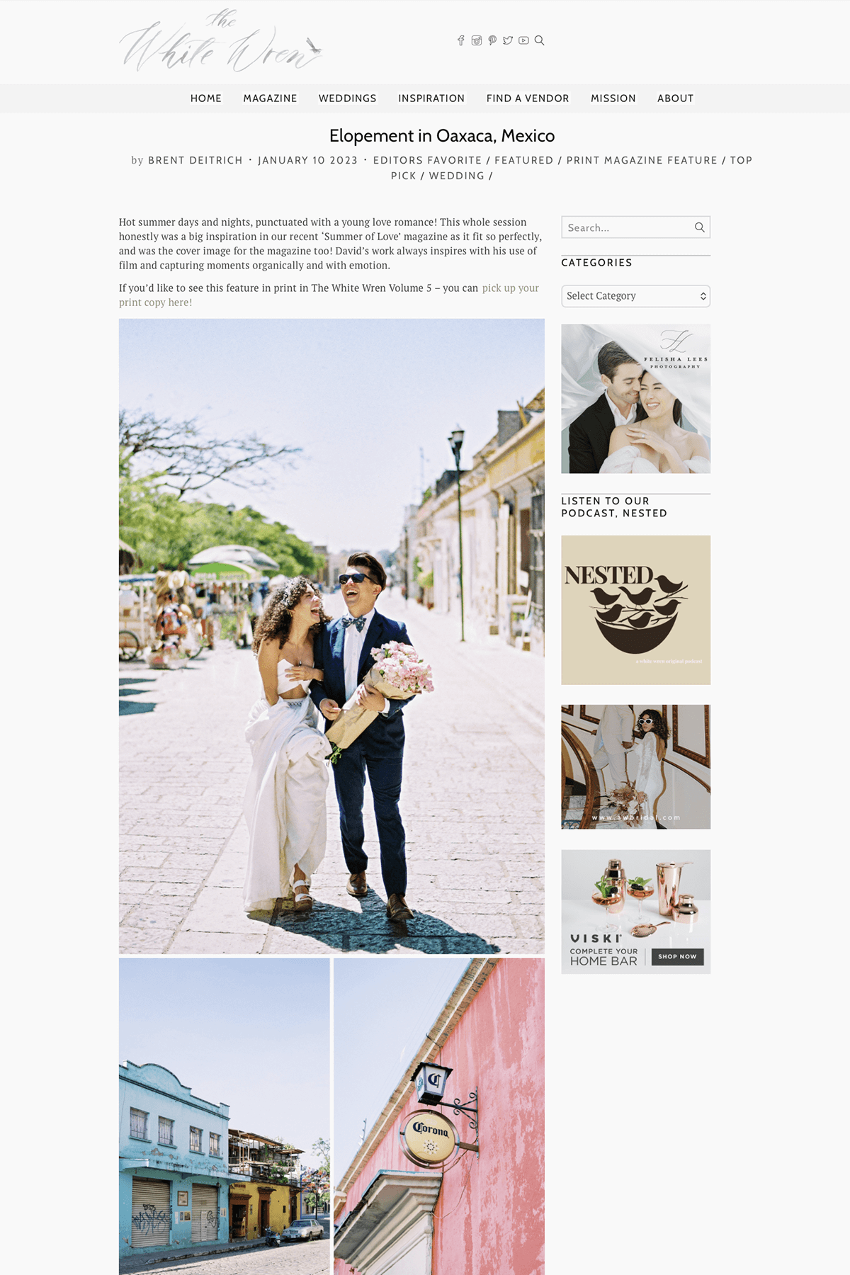 A wedding couple walking down a sunny street in Oaxaca, Mexico, with the bride in a white wedding dress and the groom in a dark suit, both smiling and laughing, holding a bouquet of pink flowers.