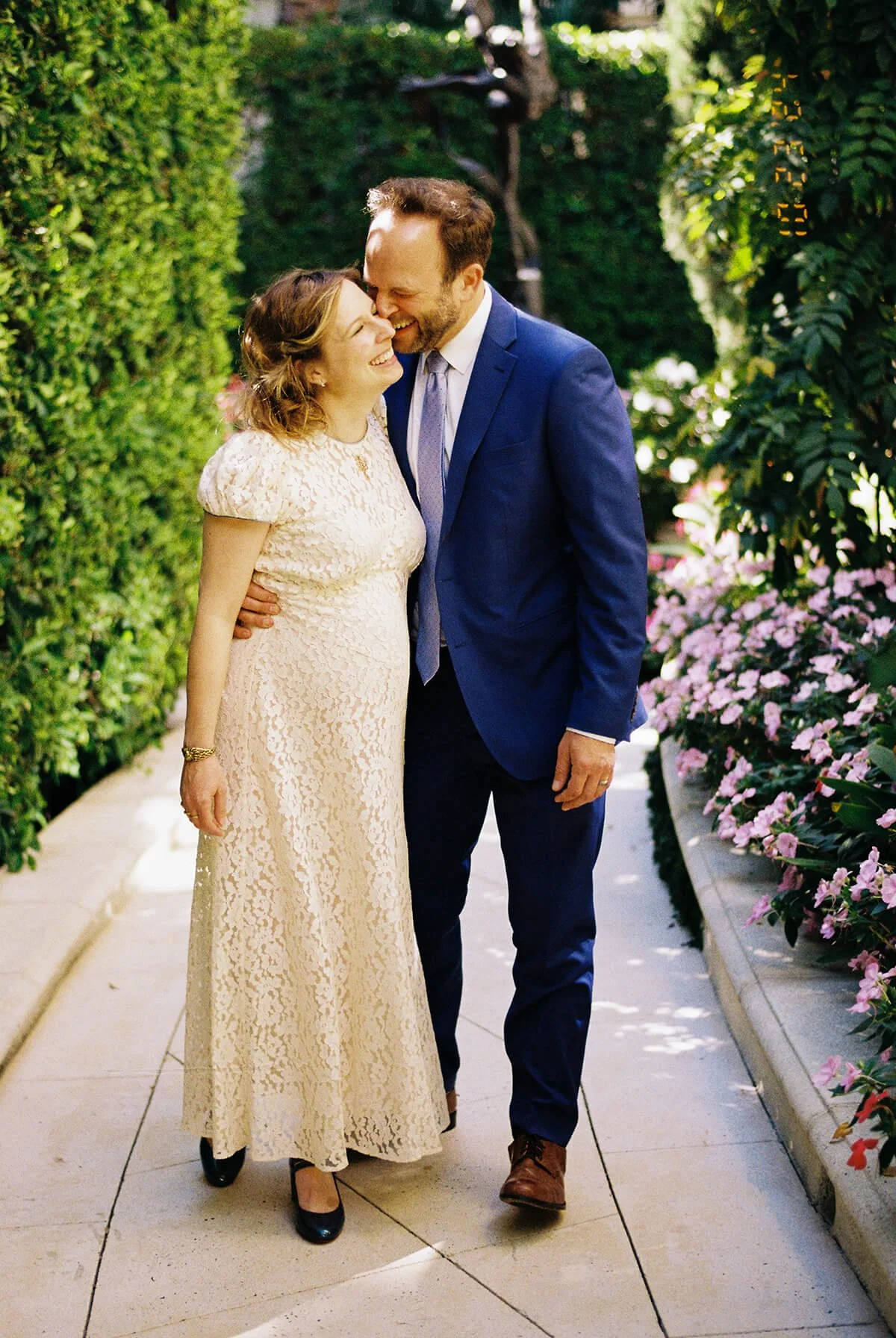 A happy couple walking together in a lush garden, sharing a joyful moment and laughing.