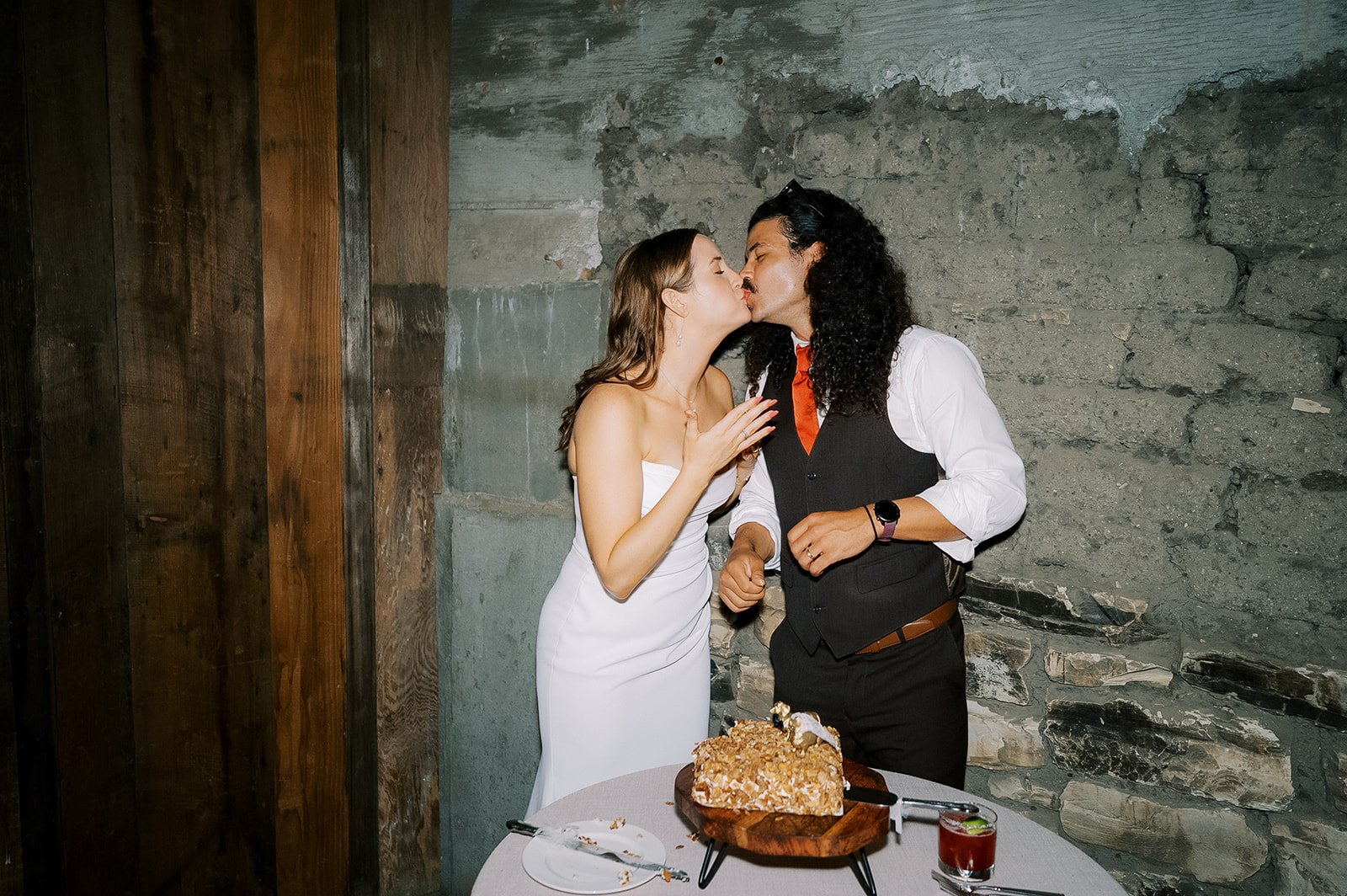 Bride and groom sharing a kiss after cake cutting to close the wedding night