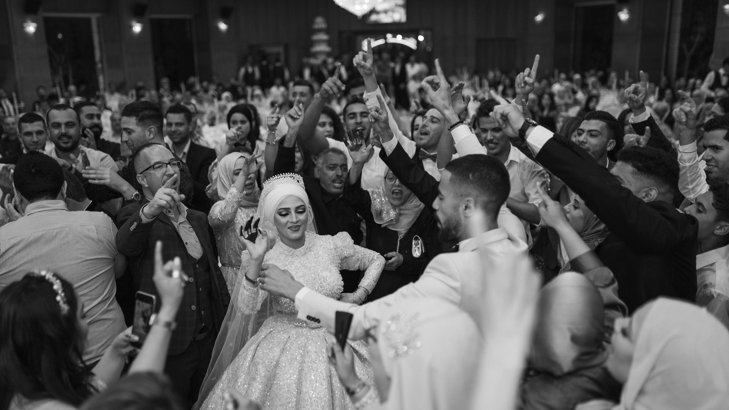 Guests dancing together on a packed dance floor at a multicultural wedding reception