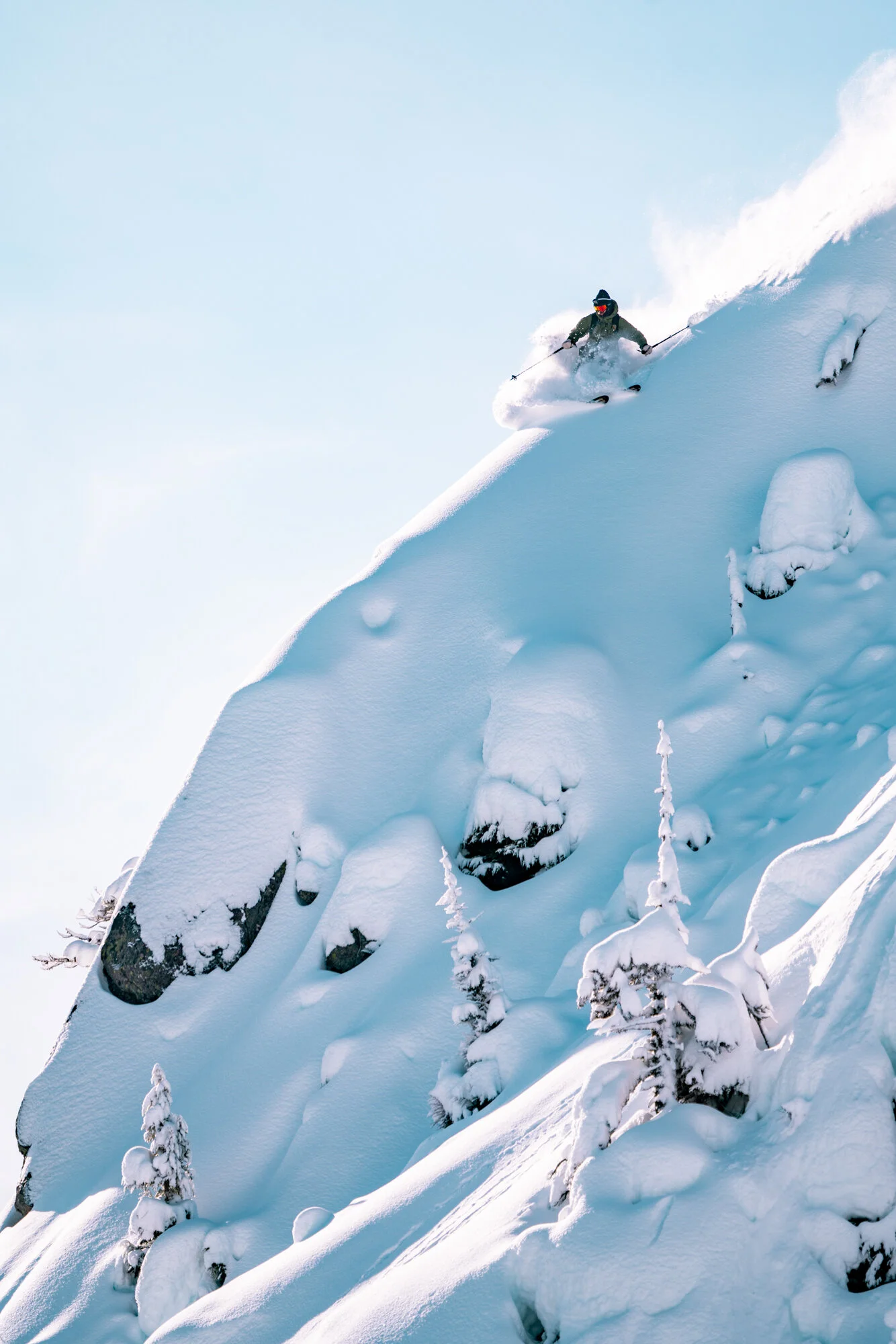 Editorial style ski photography of skier slashing powdery ridge on a bluebird day.