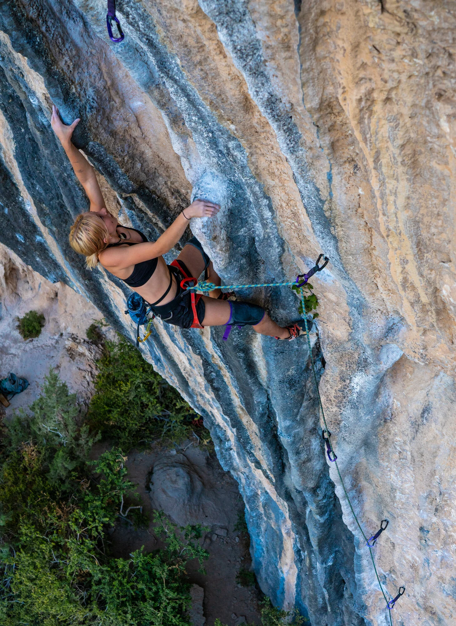 Editorial style outdoor adventure travel photography of female climber scaling blue limestone in Spain. They are sport climbing. 