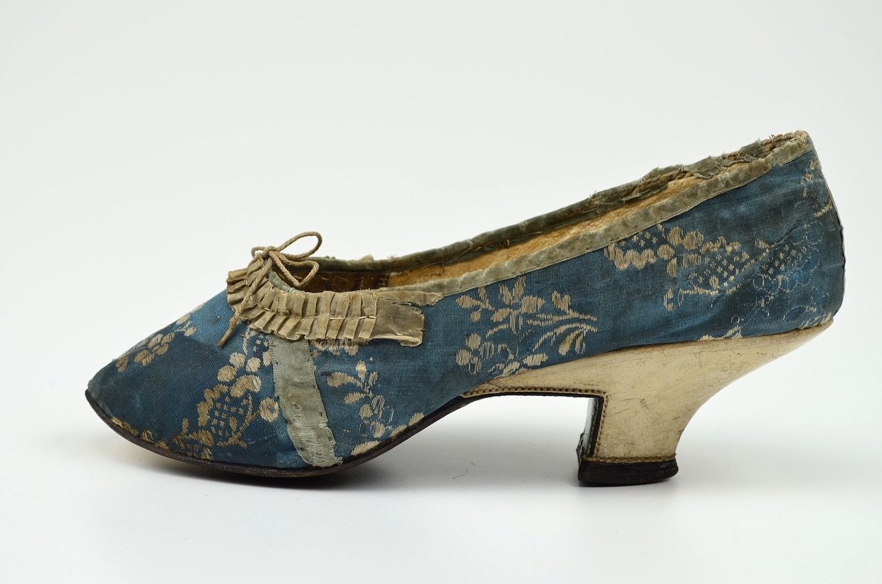 The 18th century knew all about elegance&mdash;especially when it came to shoes. Take this 1775 pair for example, housed at the Museum-Digital Deutshland. Formed from woven silk of rich, indigo blue and cream and embellished with a double ruffle ribb