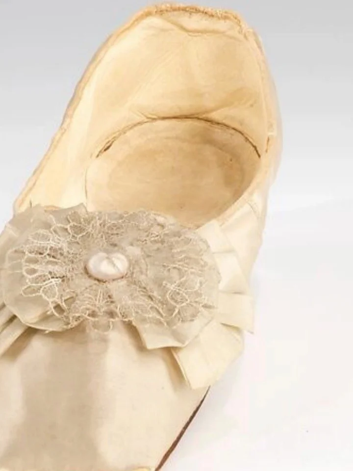 These white satin pumps would have carried a bride through her daytime ceremony and into any evening celebrations. They are light, delicate, fashionable, entirely impractical &mdash; and yet perfect for being admired.

Made in France and dating to be