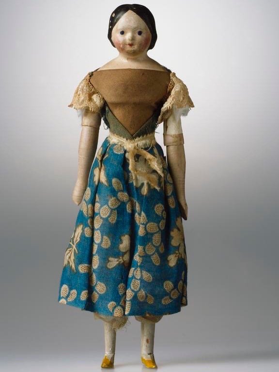 Dolls of the 1840s and 1850s have a particular stillness about them. Painted, papier-m&acirc;ch&eacute; heads with fixed expressions, soft calico or kid-leather bodies, and miniature wardrobes echoing the fashions of the day.

Many came with full tro