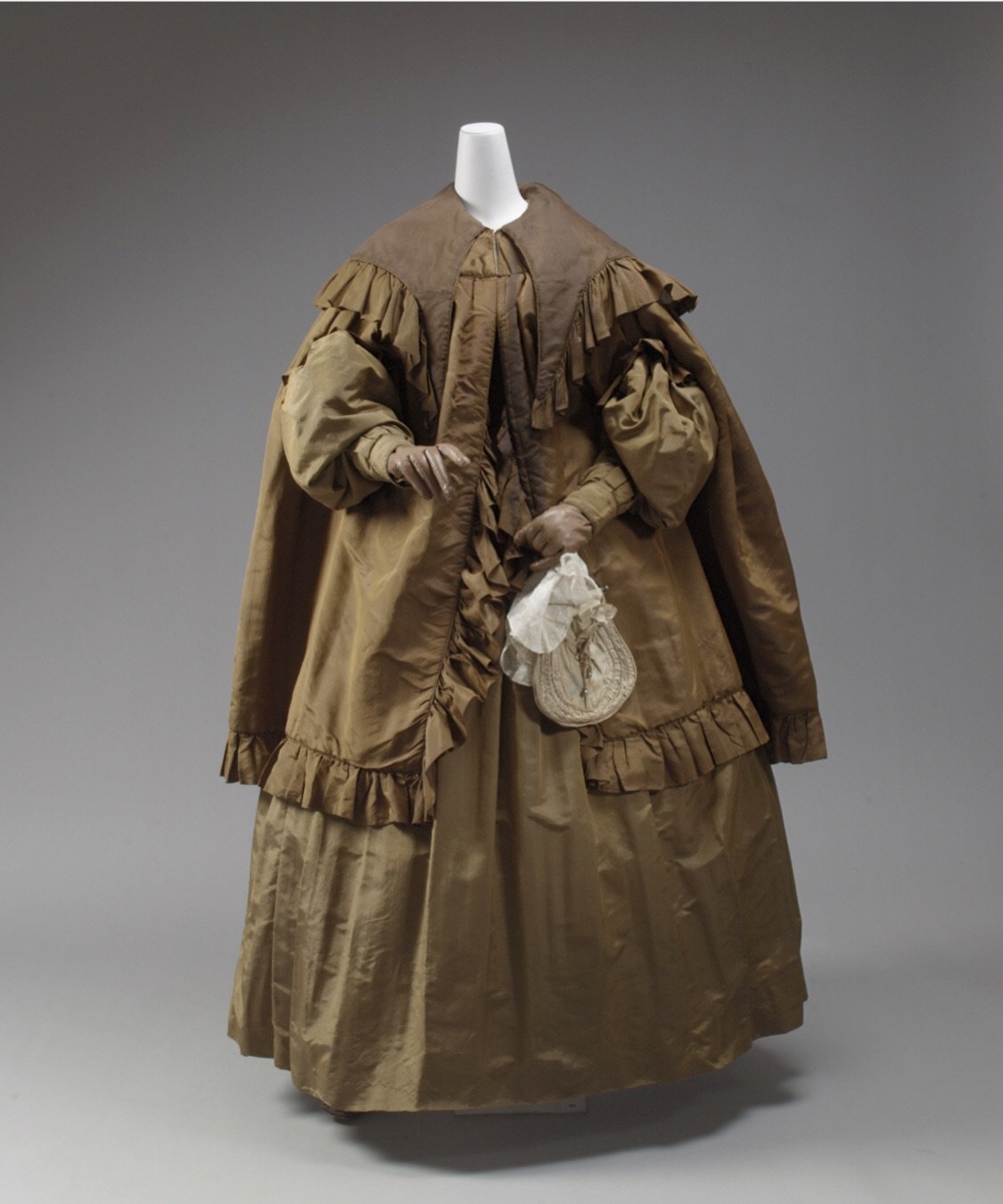 Entire outfits from the 1830s almost never survive. And yet, here we are: dress, cape, bonnet, all still together, all in (what now appears to be) rich, golden brown. (Yes, this wearer REALLY loved brown.)

The sleeves, gathered at the shoulder, are 