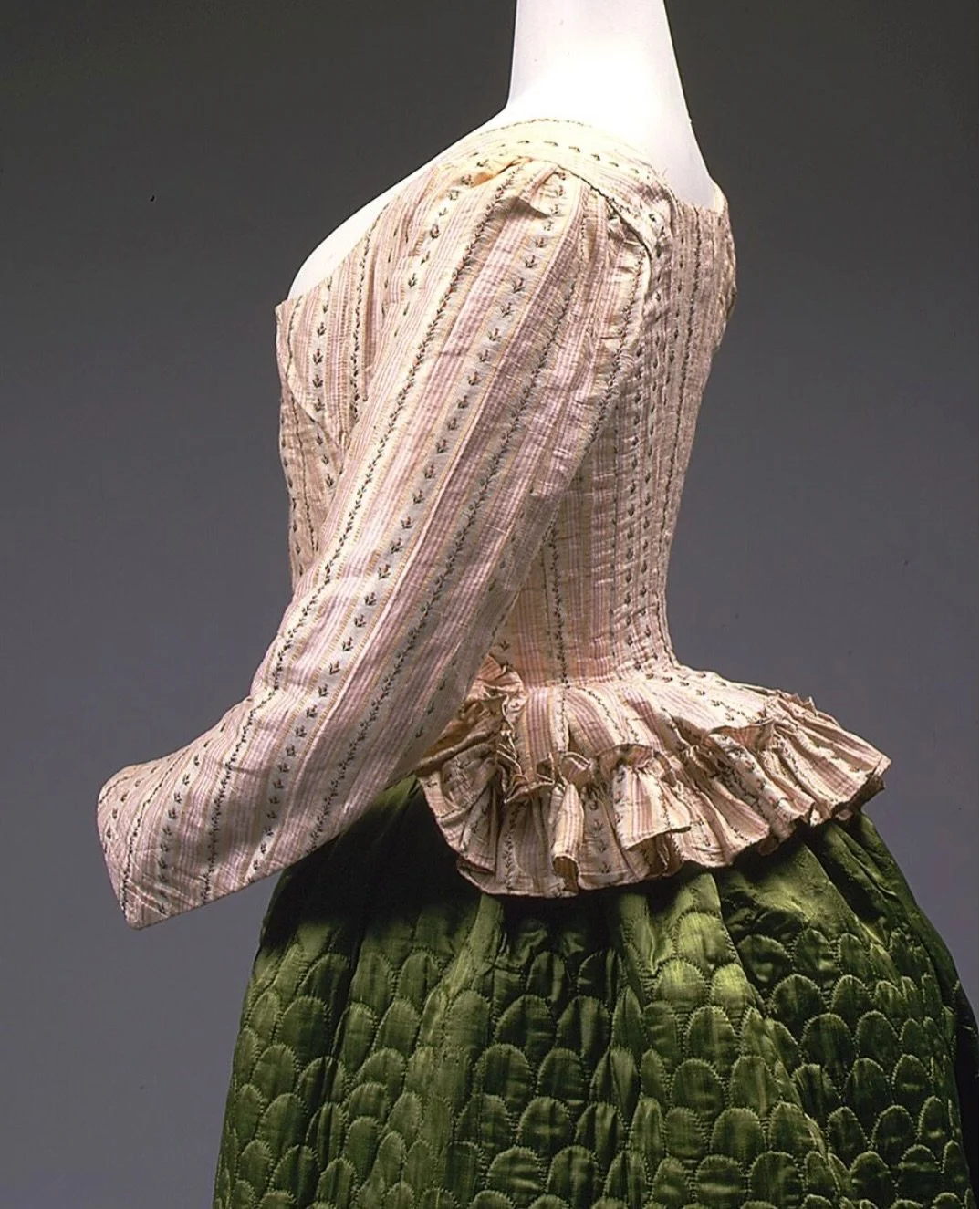 This Pierrot jacket, made in France around 1785, belongs to that brief but brilliant moment when fashion balanced structure and softness (in everyday dress at least), and just before everything changed.

The silhouette is unmistakable: fitted through