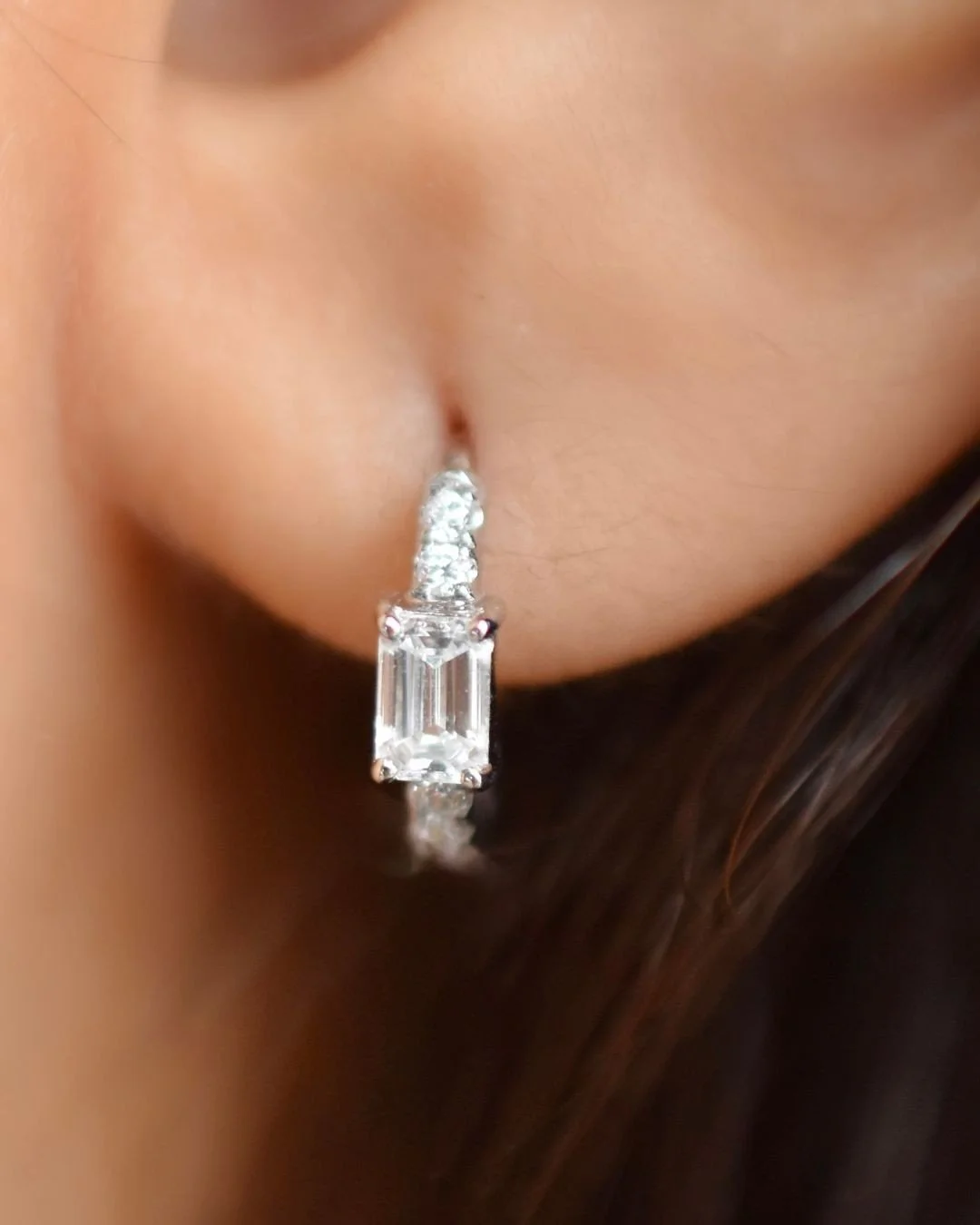 Soline white gold emerald-cut diamond huggie hoop earring worn on the ear, fine jewellery Singapore by August Bespoke