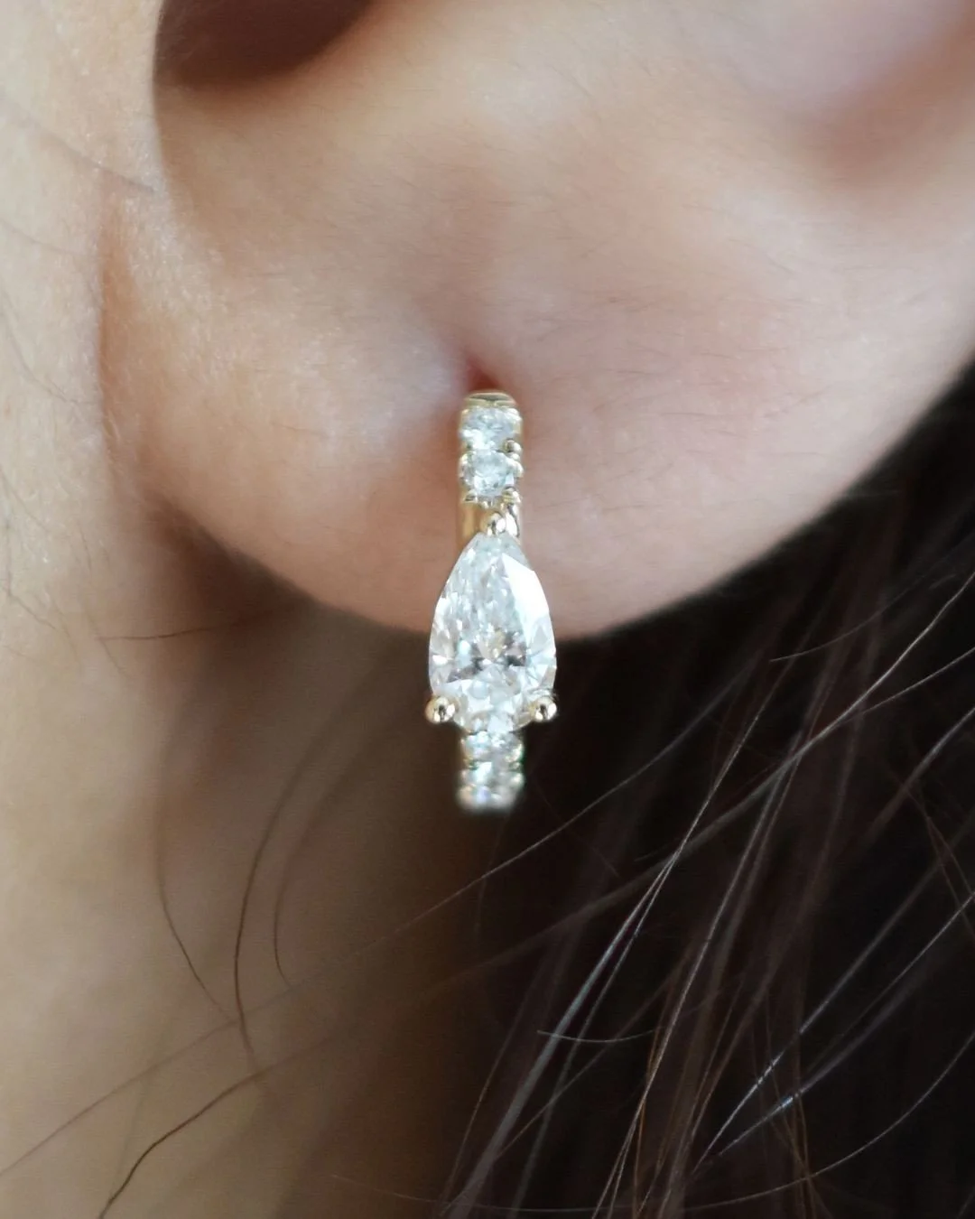 Soline yellow gold pear diamond huggie hoop earring worn on the ear, fine jewellery Singapore by August Bespoke