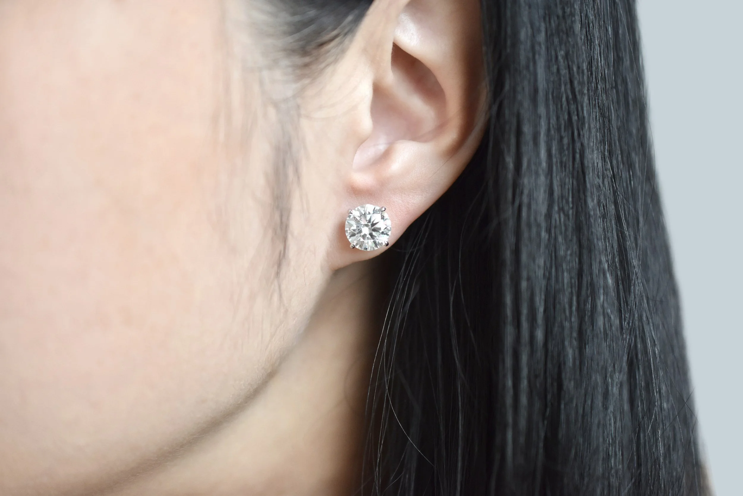 Maribelle round diamond stud earrings in white gold, worn on the ear, by August Bespoke Singapore