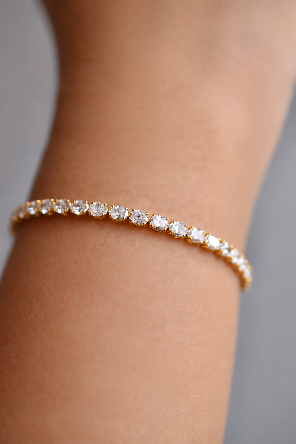 Colette east-west oval diamond tennis bracelet in yellow gold, worn on the wrist, by August Bespoke Singapore