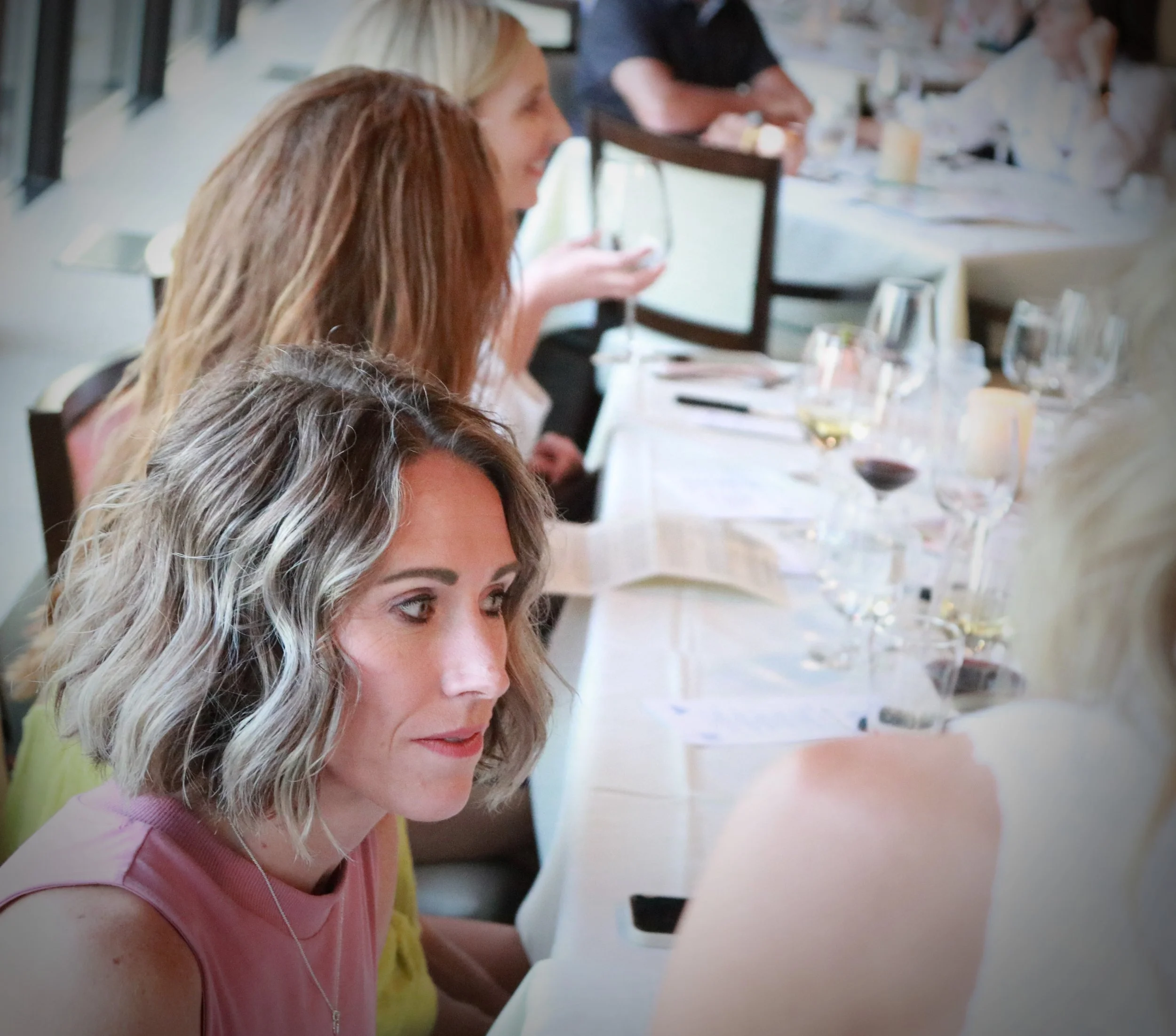 Women attending a wine tasting event with glasses of wine on the table.
