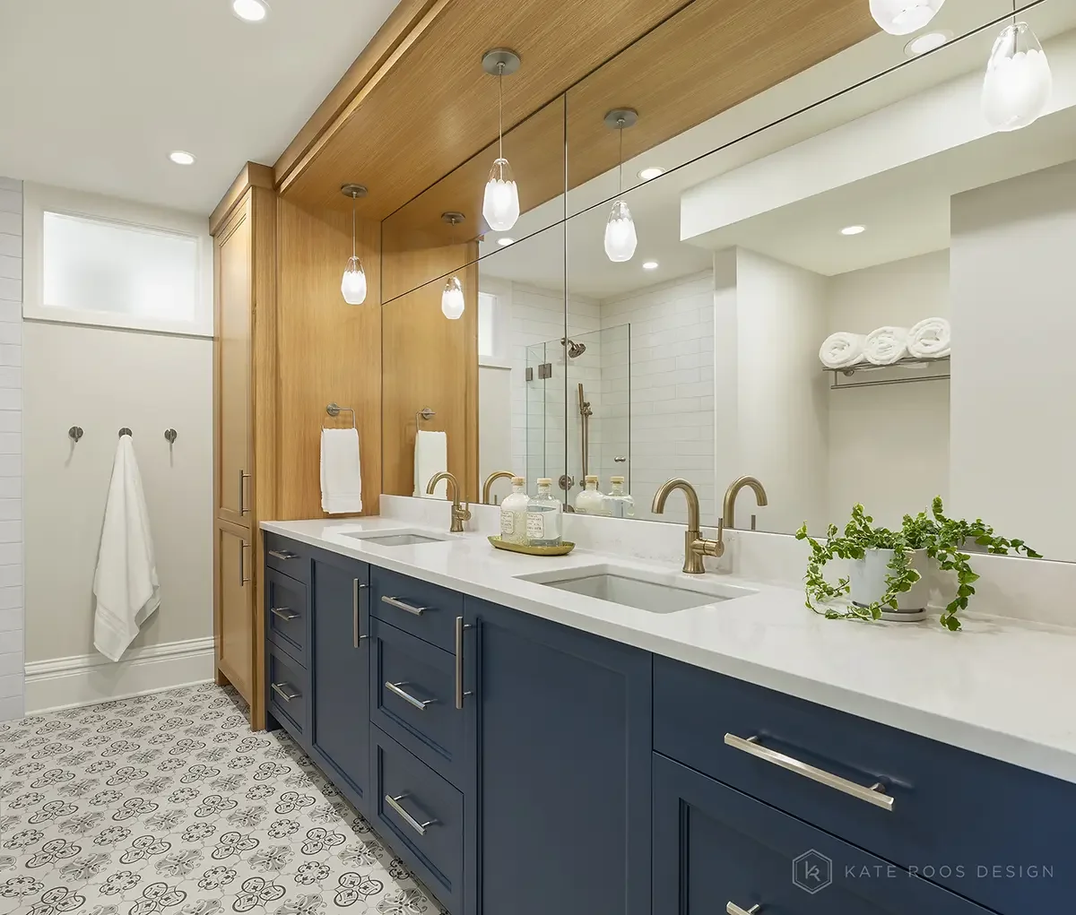 This bathroom designed by Kate Roos Design, an interior designer in Minneapolis, strikes a perfect balance between modern function and tailored warmth. The navy vanity with crisp white countertops anchors the space, while the vertical white oak cabin