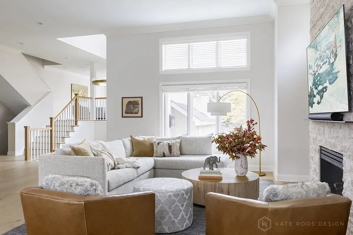 This airy and inviting living room by Kate Roos Design, an esteemed interior designer in Minneapolis, balances modern sophistication with everyday comfort. A soft neutral palette, layered with rich leathers, textured upholstery, and organic forms, cr
